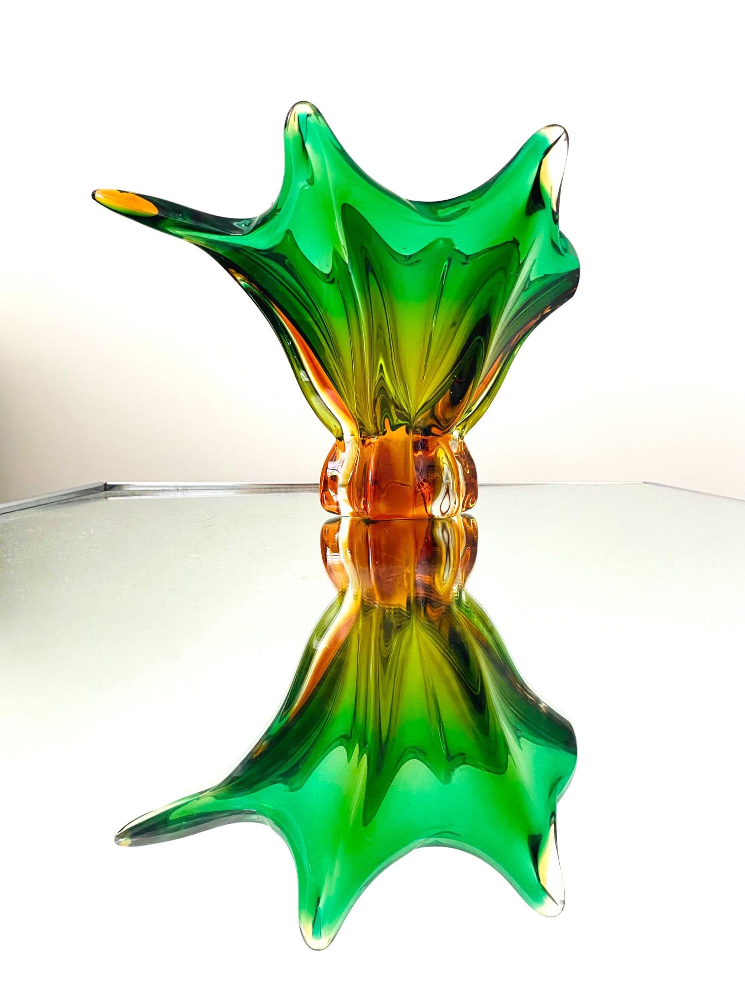 Italian Mid-Century Modern footed bowl or vase in handblown Murano glass. The vase has an abstract floral form reminiscent of a lily. Comprised of clear glass with Sommerso technique with submerged colors orange amber and vibrant emerald green.