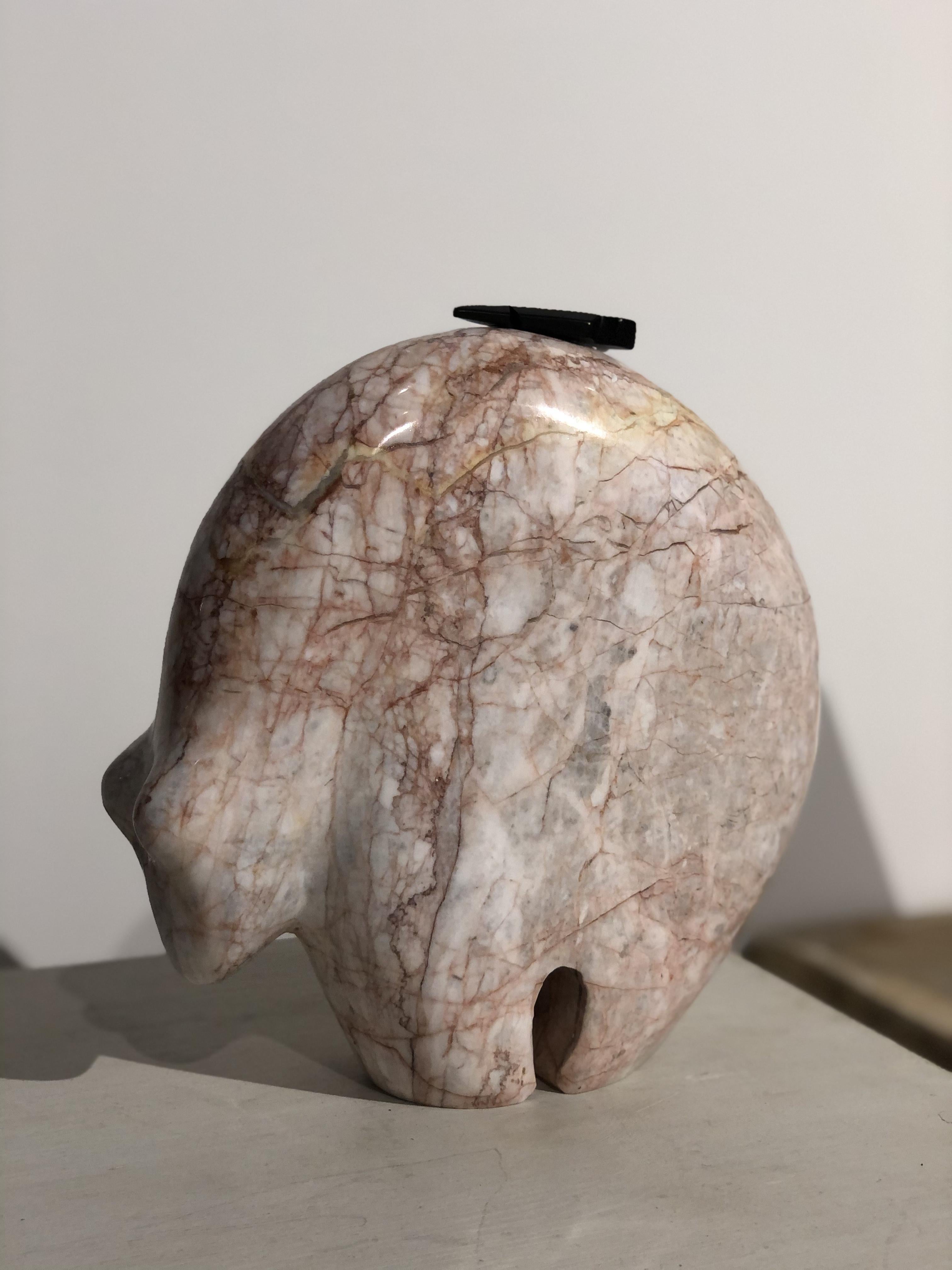 A playful abstract bear figurine carved from polished pink marble bear. Organic form with a rounded back, minimal features, and a black arrow perched on its back. Made in the mid-20th century in a modern abstract style.