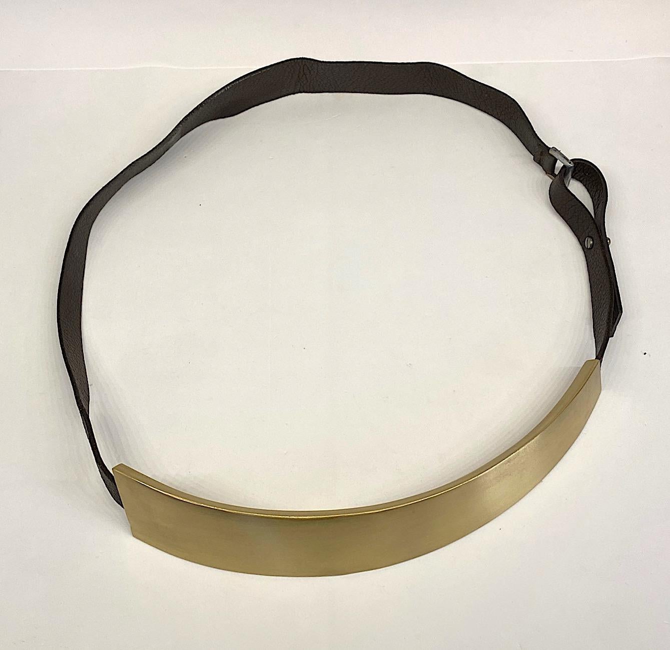 A truly unique statement belt from the 1980s. The belt is a satin finish brass and leather. The front piece is a 2.5 inches wide on one side, 1.25 inches wide on the opposite end and 12 inches long. It is curved to fit around the body comfortably.