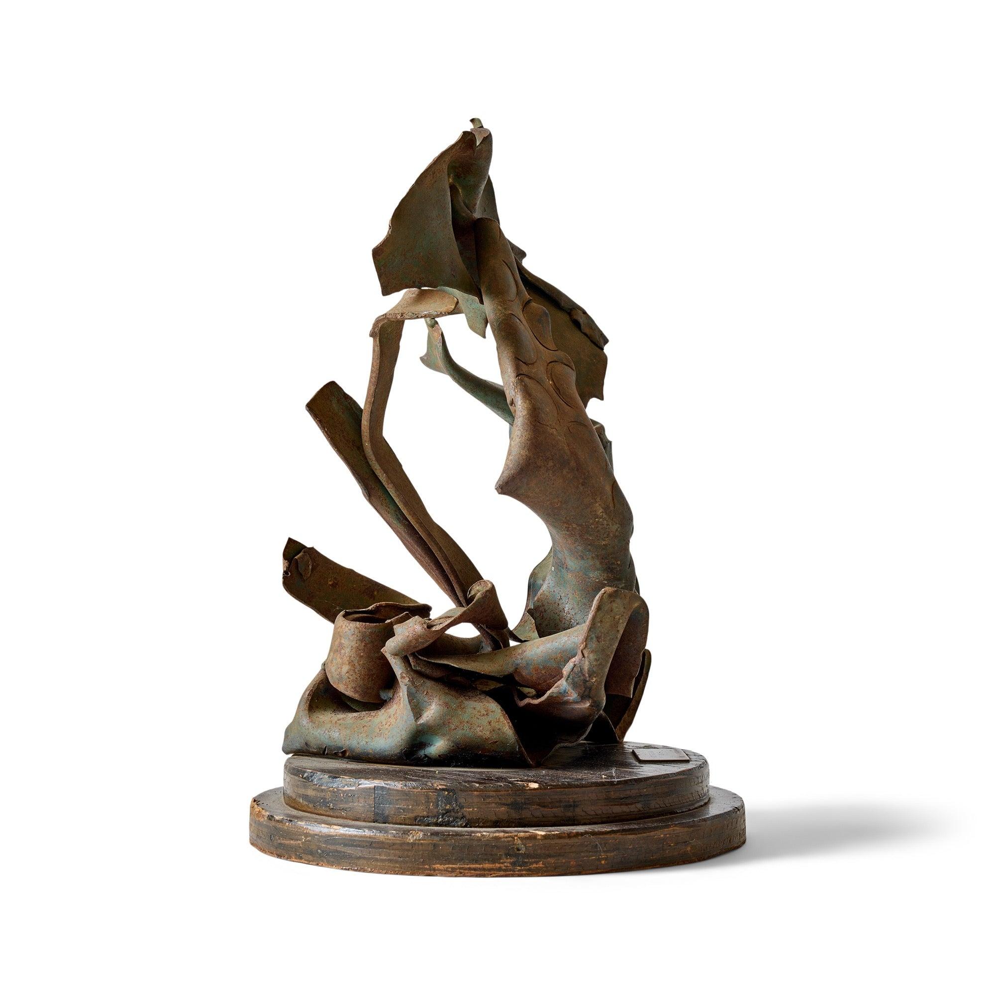 Sculpture abstraite en métal sur une base ronde en bois.