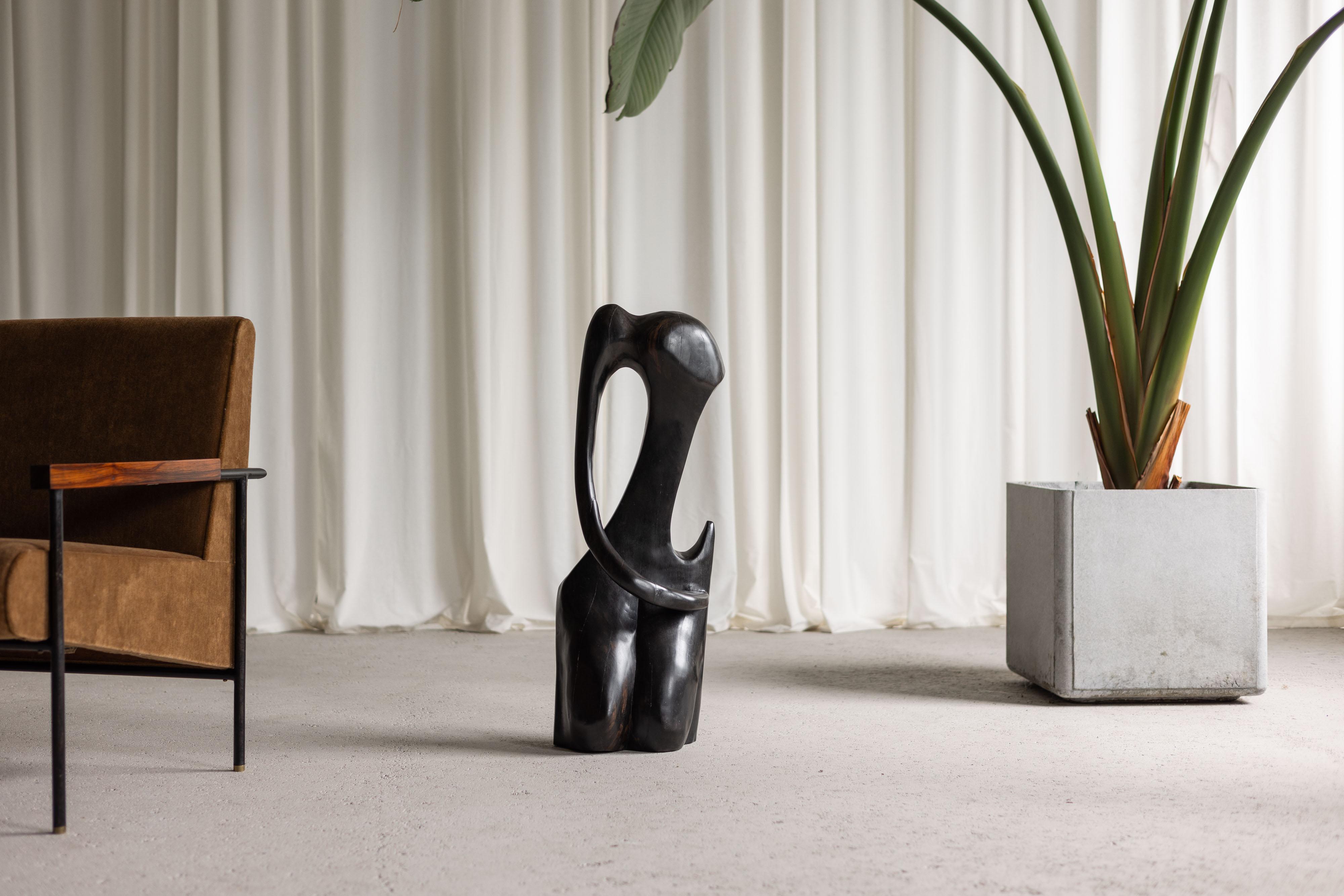 Behold the captivating allure of this abstract mid-century modern sculpture, crafted from solid ebony wood by an unknown artist in France in the 1960s. This exquisite piece takes the form of a female torso, elegantly abstracted yet undeniably