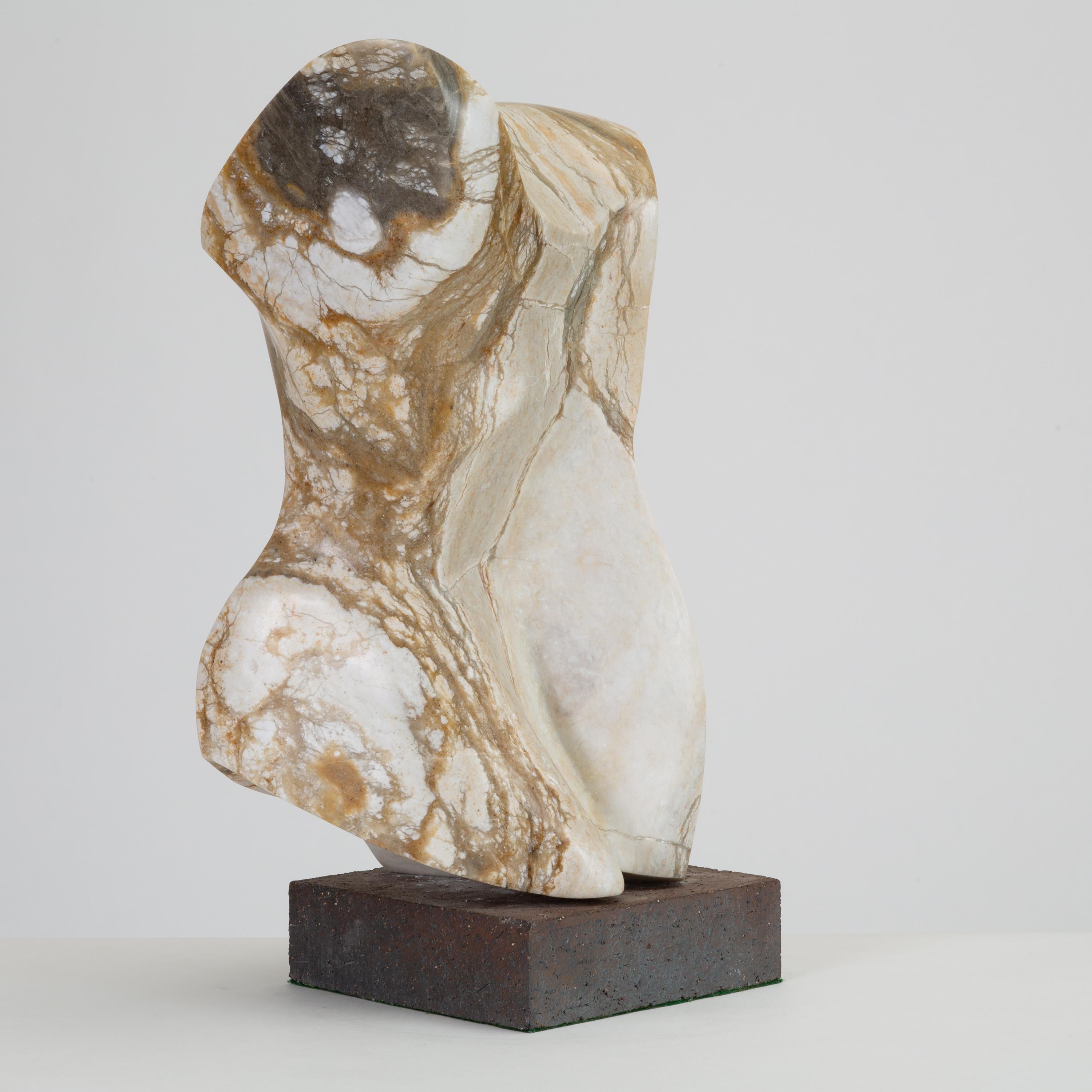 A spectacularly veined gray marble sculpture, touched with notes of ochre and cinnamon. The abstracted form, mounted on a gray brick base, recalls a Greek or Roman torso figure. Signed 