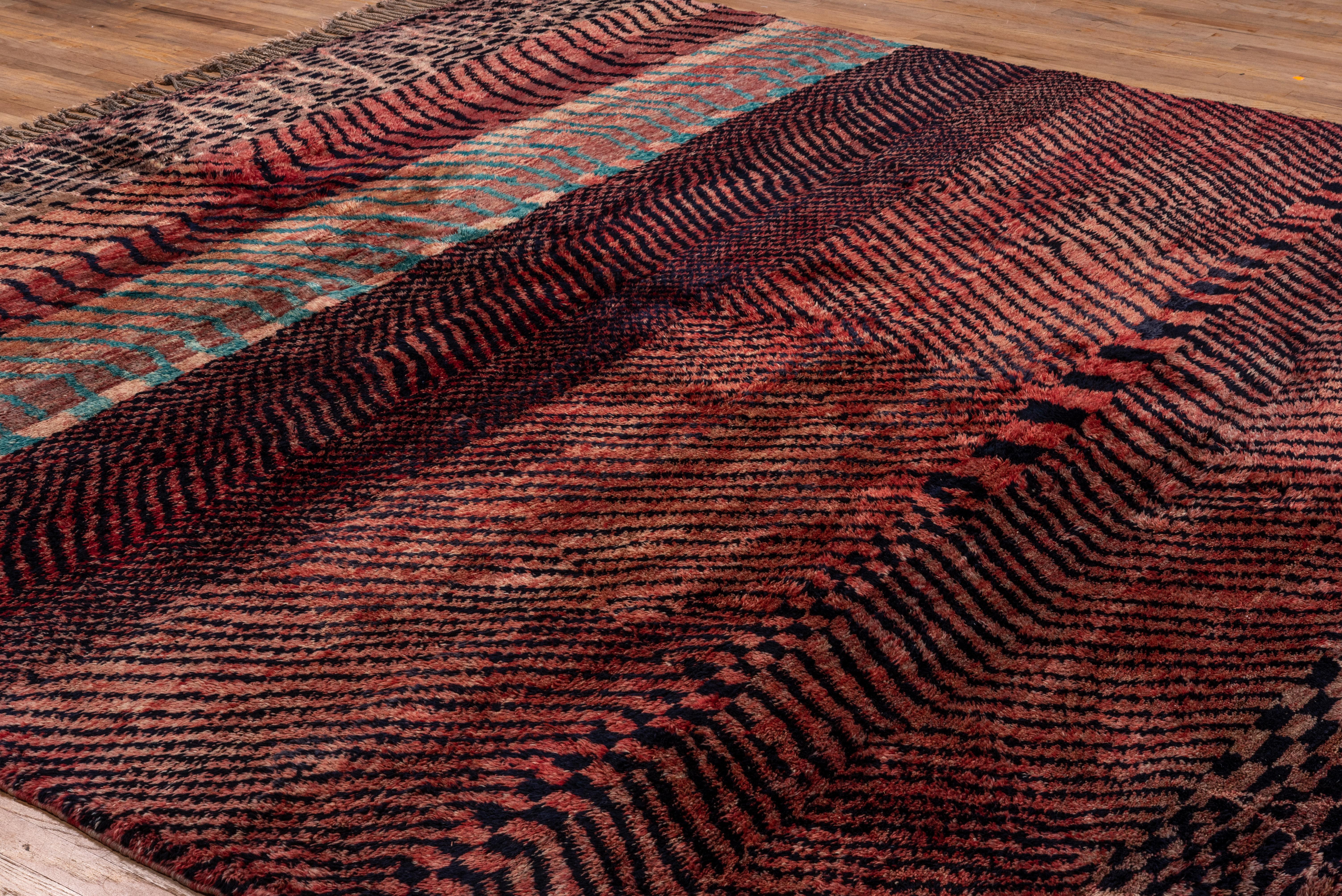 New production and high quality rug woven in Morocco with tones of gray, b lack, and variations of corals reds and pink. Excellent brand new condition.