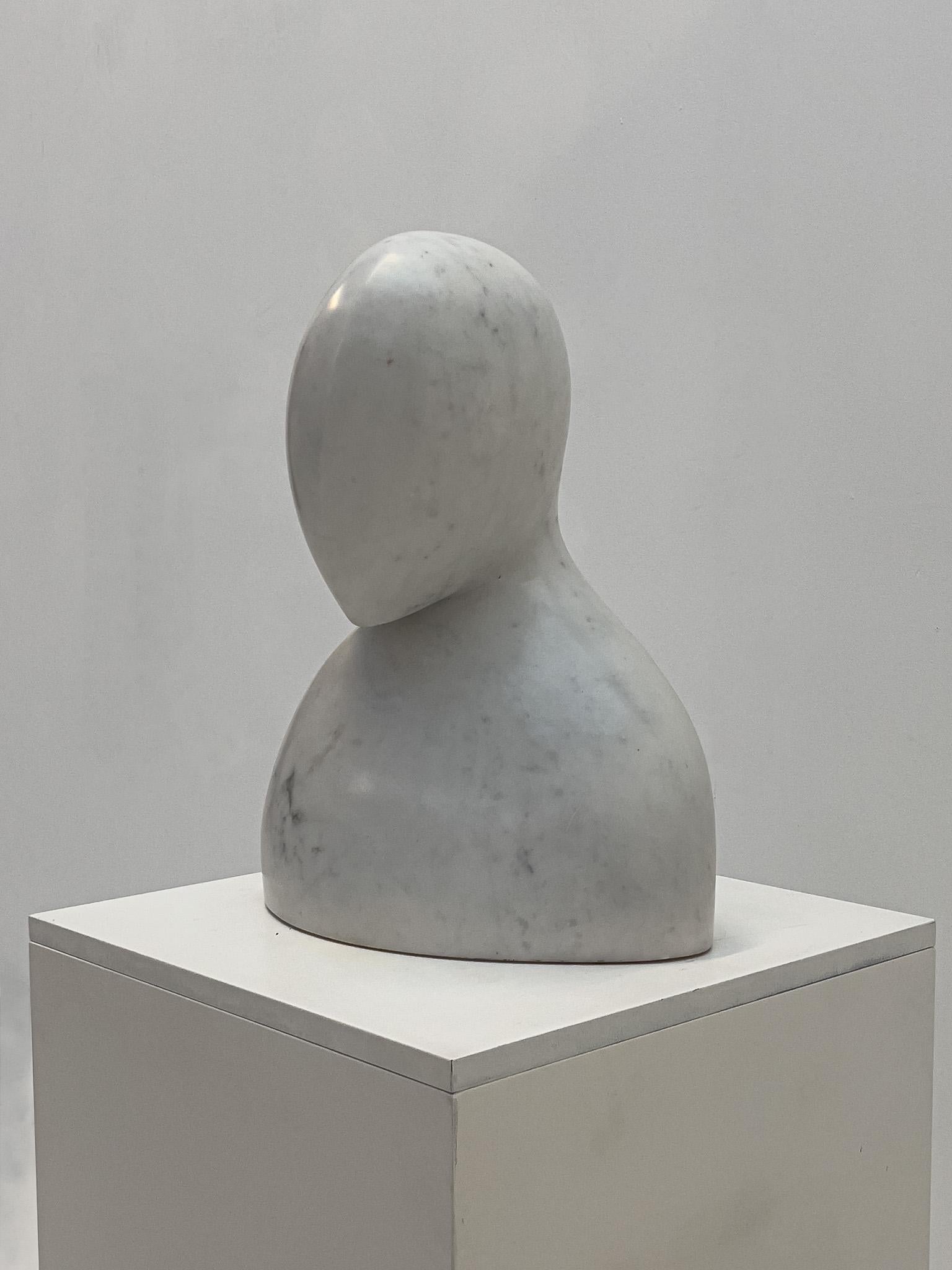 This abstract white marble bust, crafted circa 1970, is a striking example of mid-20th-century sculpture. The piece features a minimalist, stylized human form with a smooth, rounded head and softly contoured torso, showcasing the elegance of