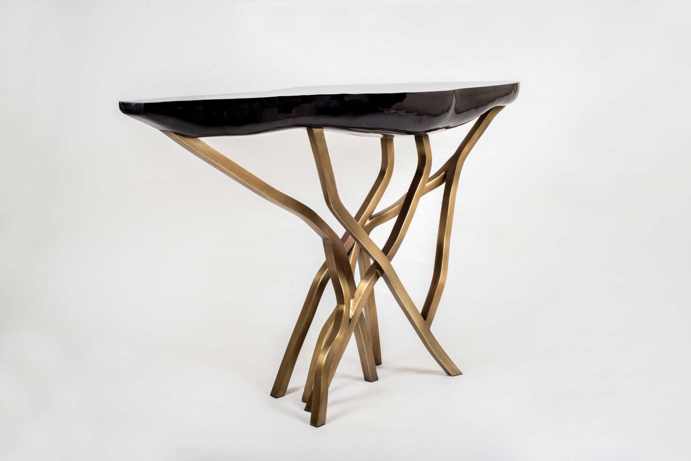 The Acacia console table makes for a dramatic statement piece in any space. The amorphous shaped top is in black pen shell and the organic shaped legs are in bronze-patina brass. The shell parts are hand selected before being inlaid, creating