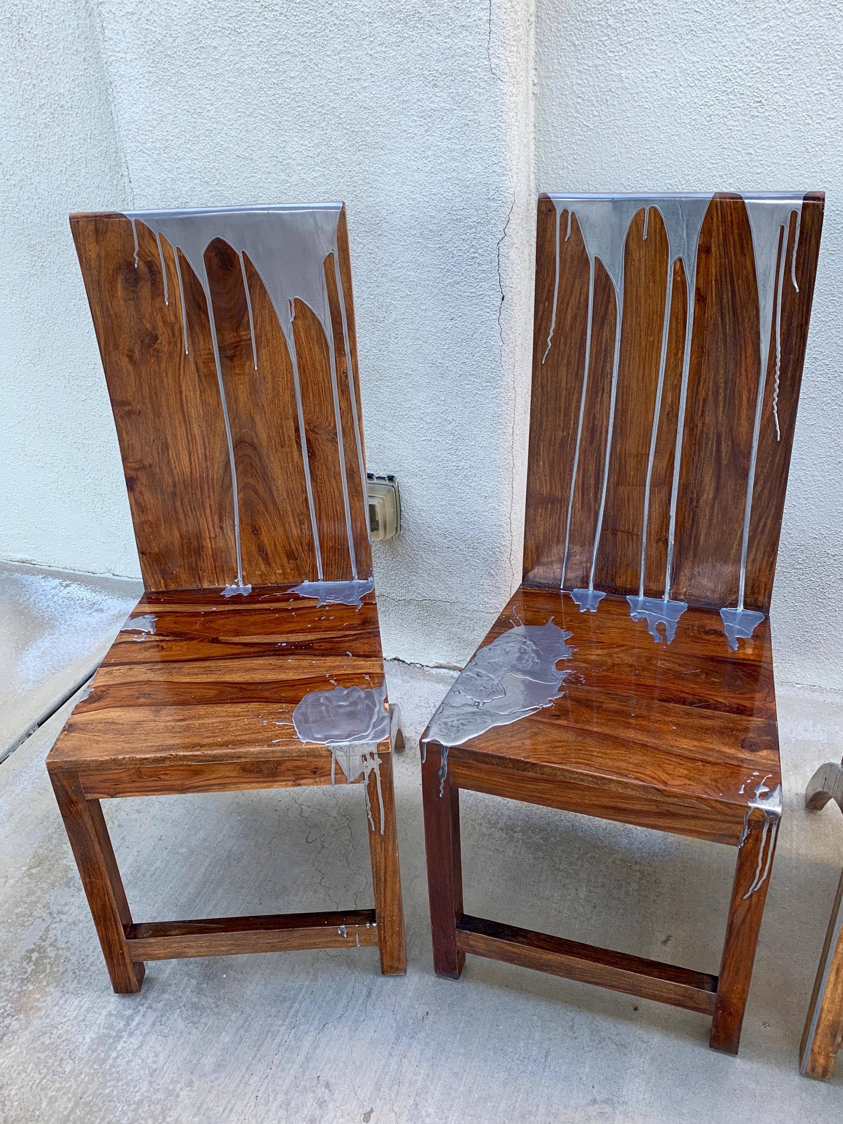 A set of 4 dining or side chairs in hand built from the hard Acacia wood species and decorated in dripped steel metal by a local Palm Springs artisan. These chairs have had metal applied to them and then polished. They are each unique hand decorated