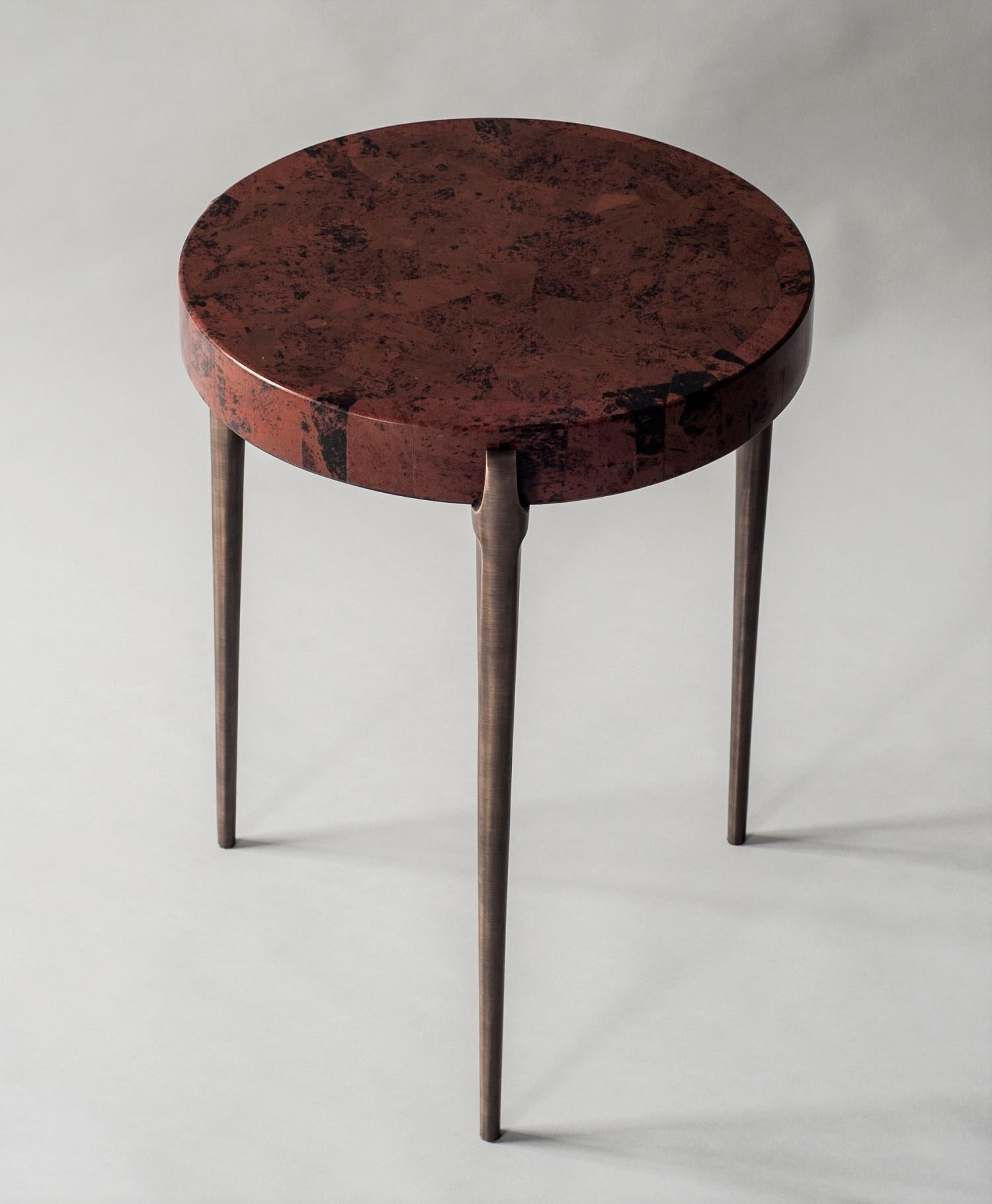 The Acantha side table’s recessed top sits precisely within the supports of three hand-cast bronze legs. The minimal lines of this piece are designed to highlight the natural beauty of the Marconi tabletop, a semi-precious stone with rich red and