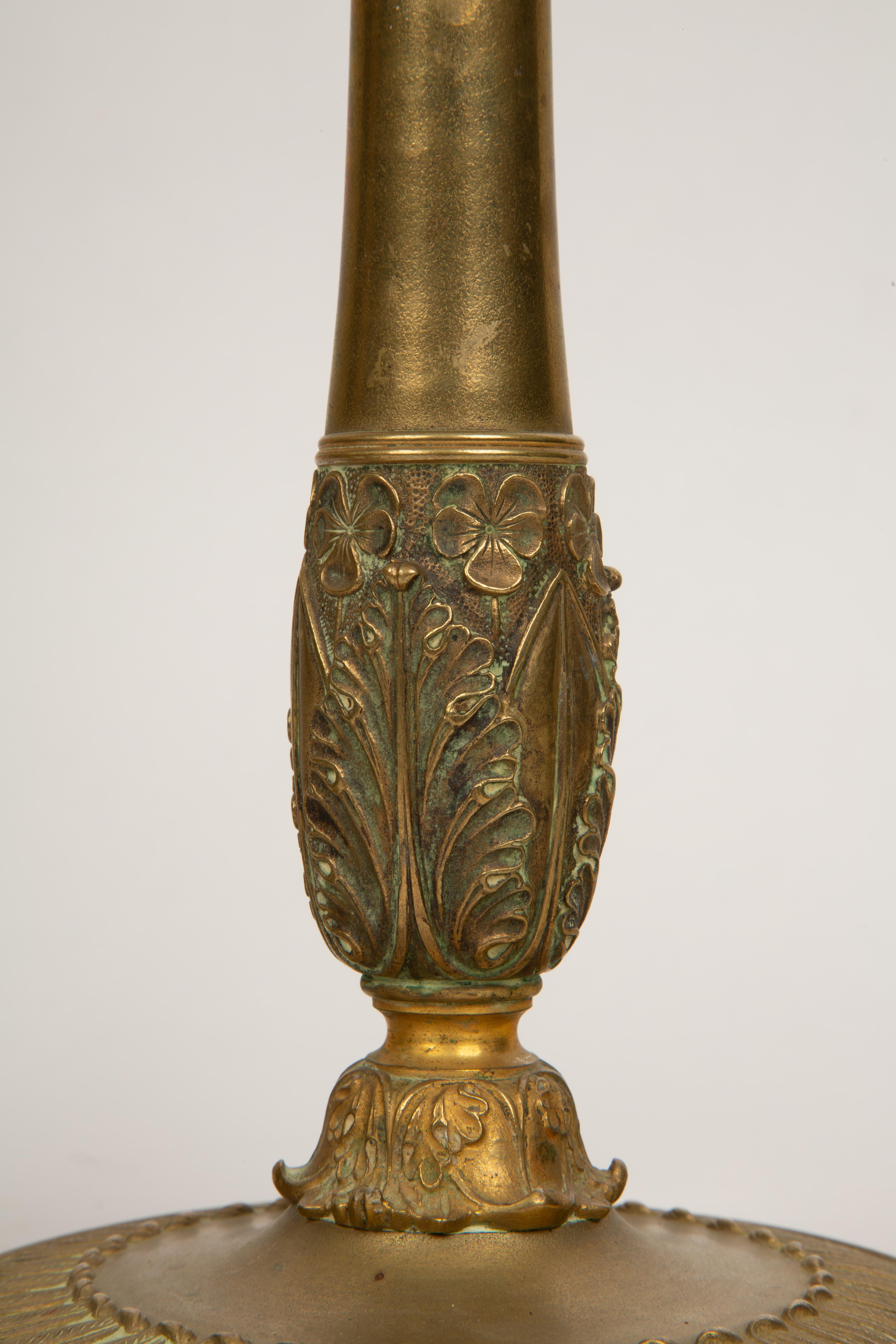 Questa elegante coppia di **candelieri della Restaurazione francese del XIX secolo** è magistralmente realizzata in bronzo cesellato, riflettendo la raffinata arte dell'epoca. Ogni candeliere è caratterizzato da una colonna affusolata che si erge da