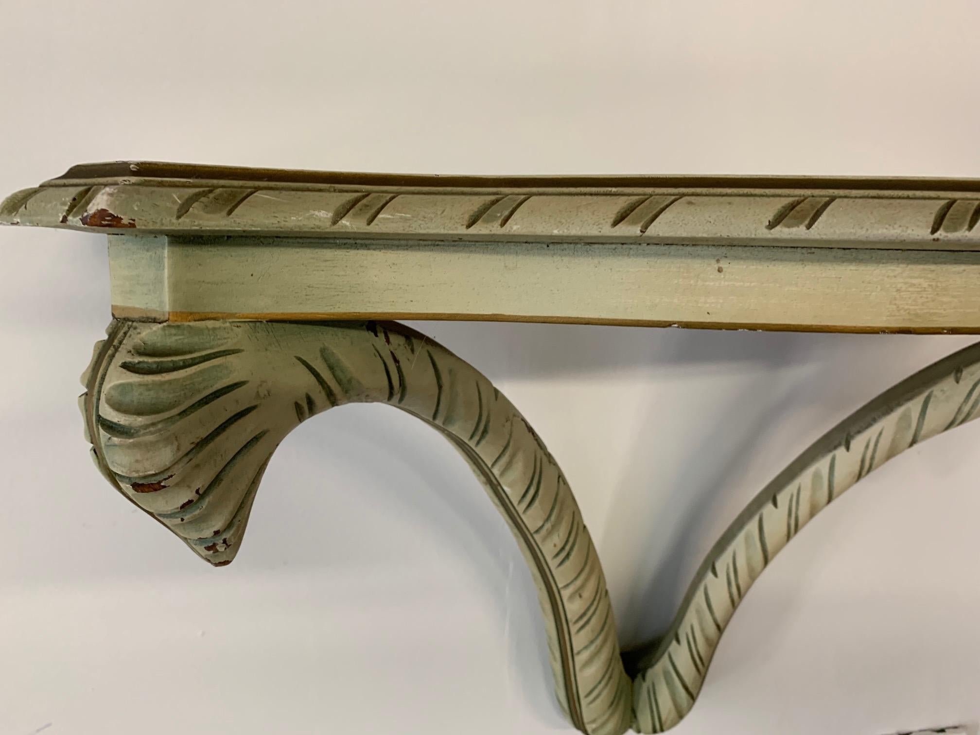 Decorative wall shelf in the manner of Dorothy Draper features carved acanthus leaf detailing and is in very good vintage condition with minor imperfections consistent with age.
