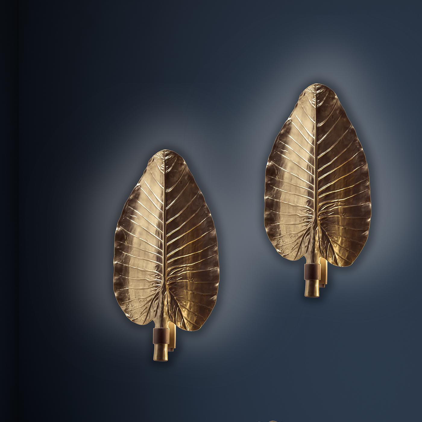Evoking exotic landscapes and exuding a sophisticated allure, this sconce was superbly crafted of brass and porcelain to render the shape and texture of a banana leaf. The light shining inside from the single bulb reflects onto the concave