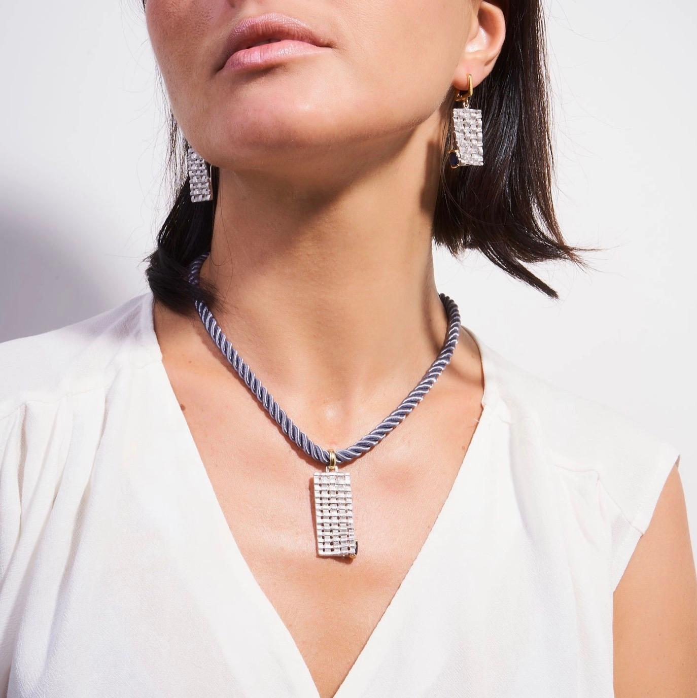 Accalia Blue Sapphire Woven Pendant, by German Kabirski  

This dramatic pendant has been handcrafted by expressive artisans in white rhodium and gold. This bold piece is carefully encrusted with pretty blue sapphire gemstones that offer their