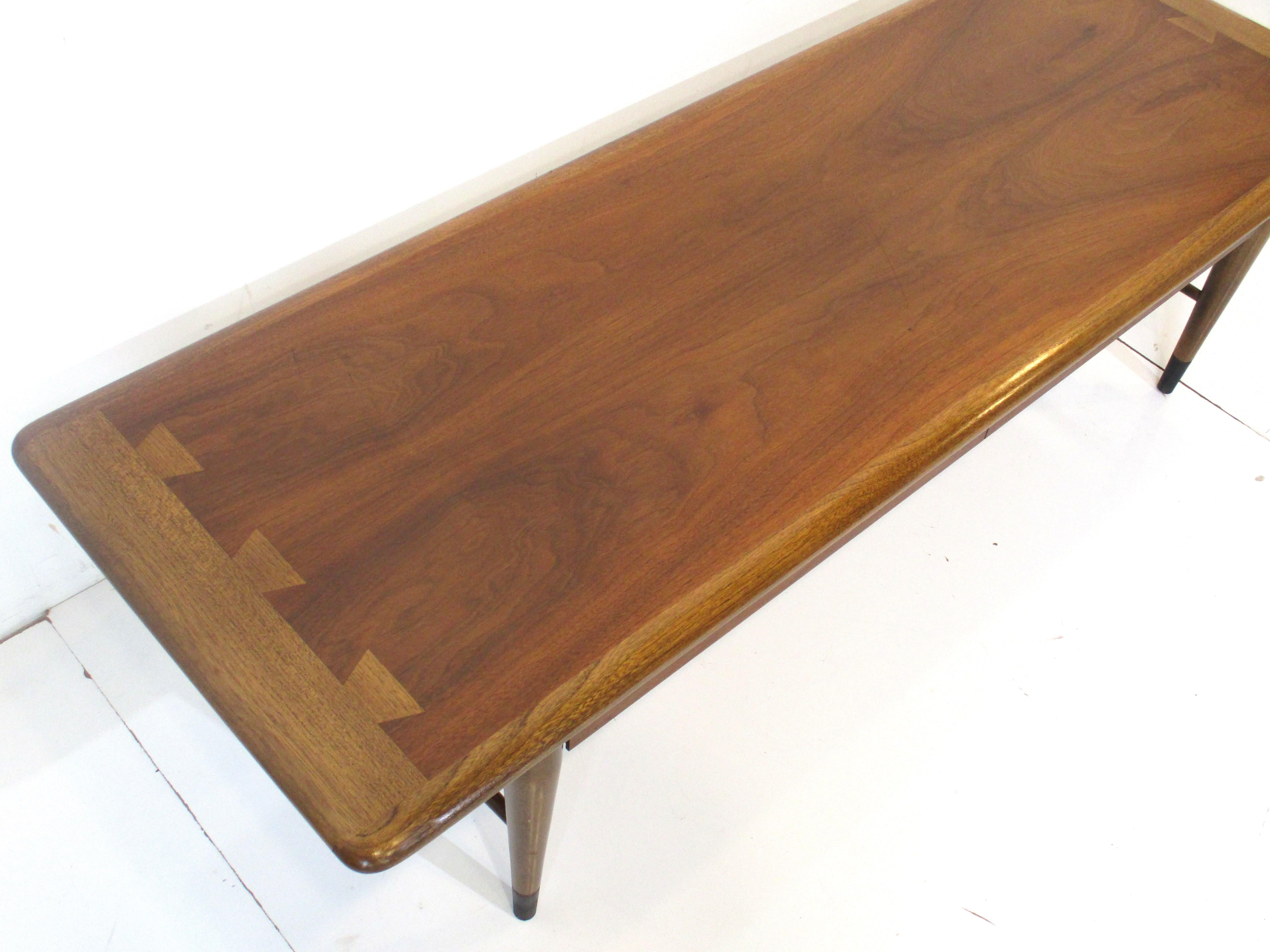 A very well crafted walnut and light mahogany long coffee table from Lane's signature Acclaim collection. The Acclaim pieces have the contrasting dovetail top design which give the piece that sharp handmade feel that the designer Andre Bus is noted