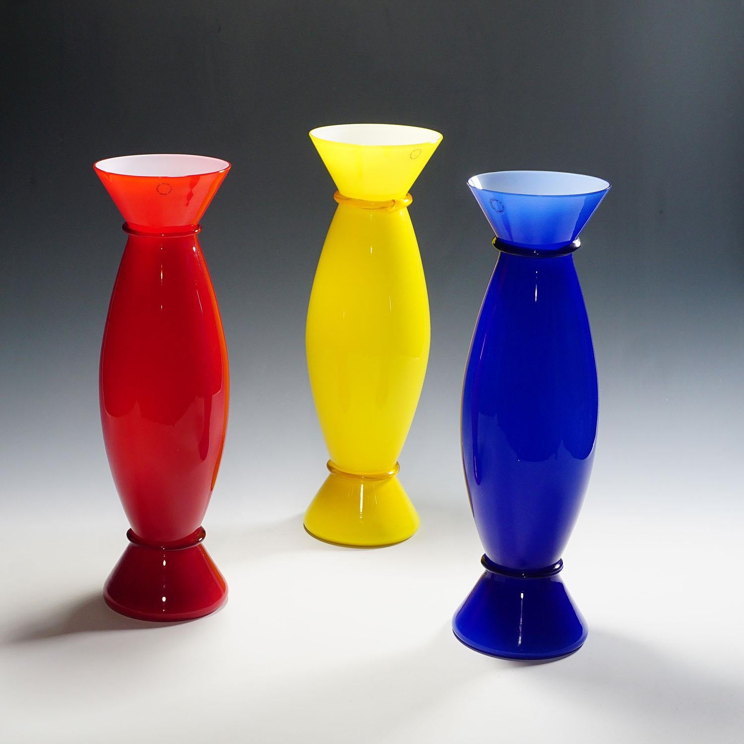 A set of three Acco Vases designed in 1988 by Alessandro Mendini for Venini, Venice. White opaque glass with colorful overlays in red, yellow and blue and a clear glass finish. All three with incised signature 'venini 88, 89 and 90' on the base and