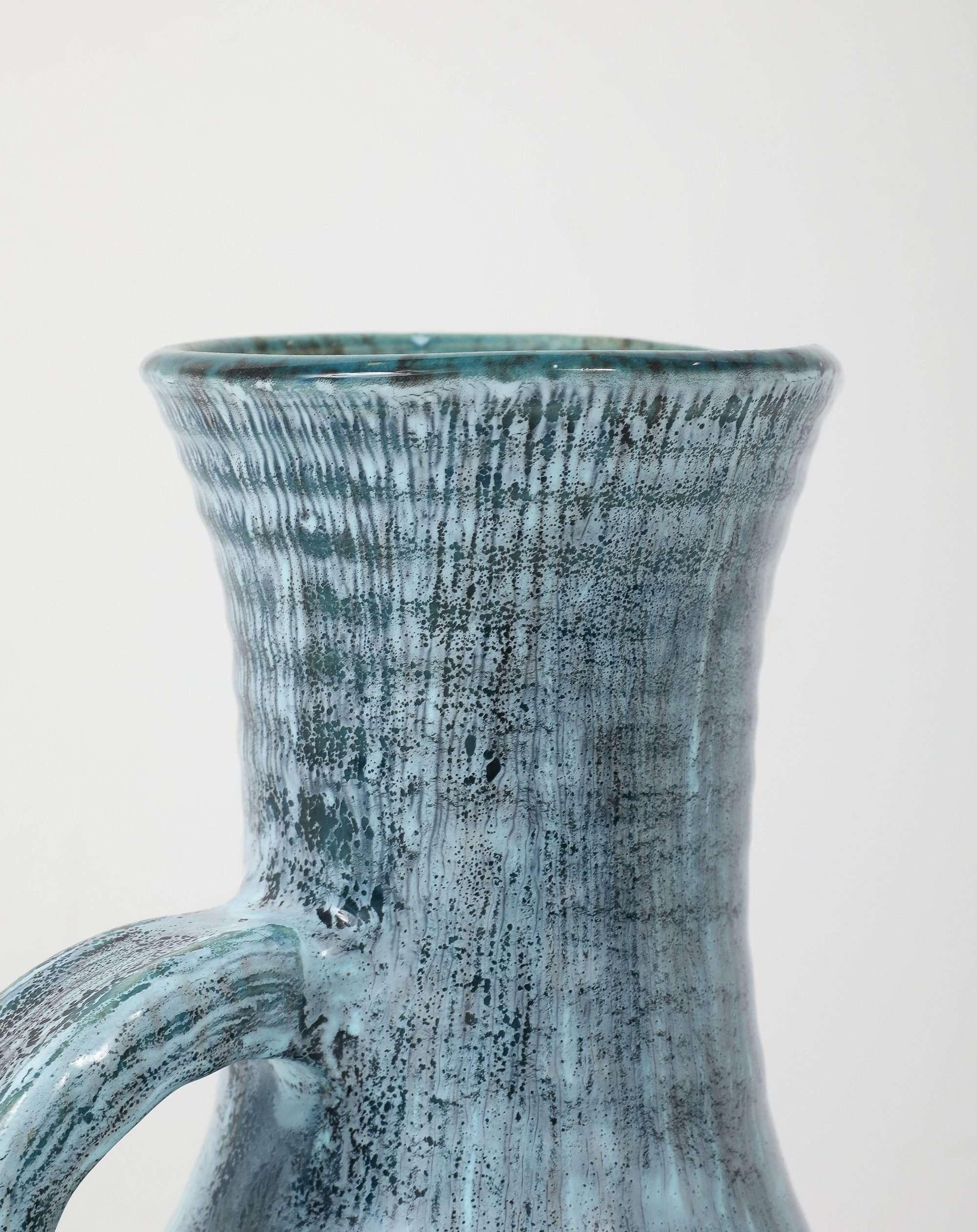 Hand-thrown in the celebrated Burgundy village of Accolay, this tall stoneware pitcher epitomises French studio ceramics of the early 1950s. The body of the vase features a combed, vertical texture and a flared collar anchored by a sculptural,
