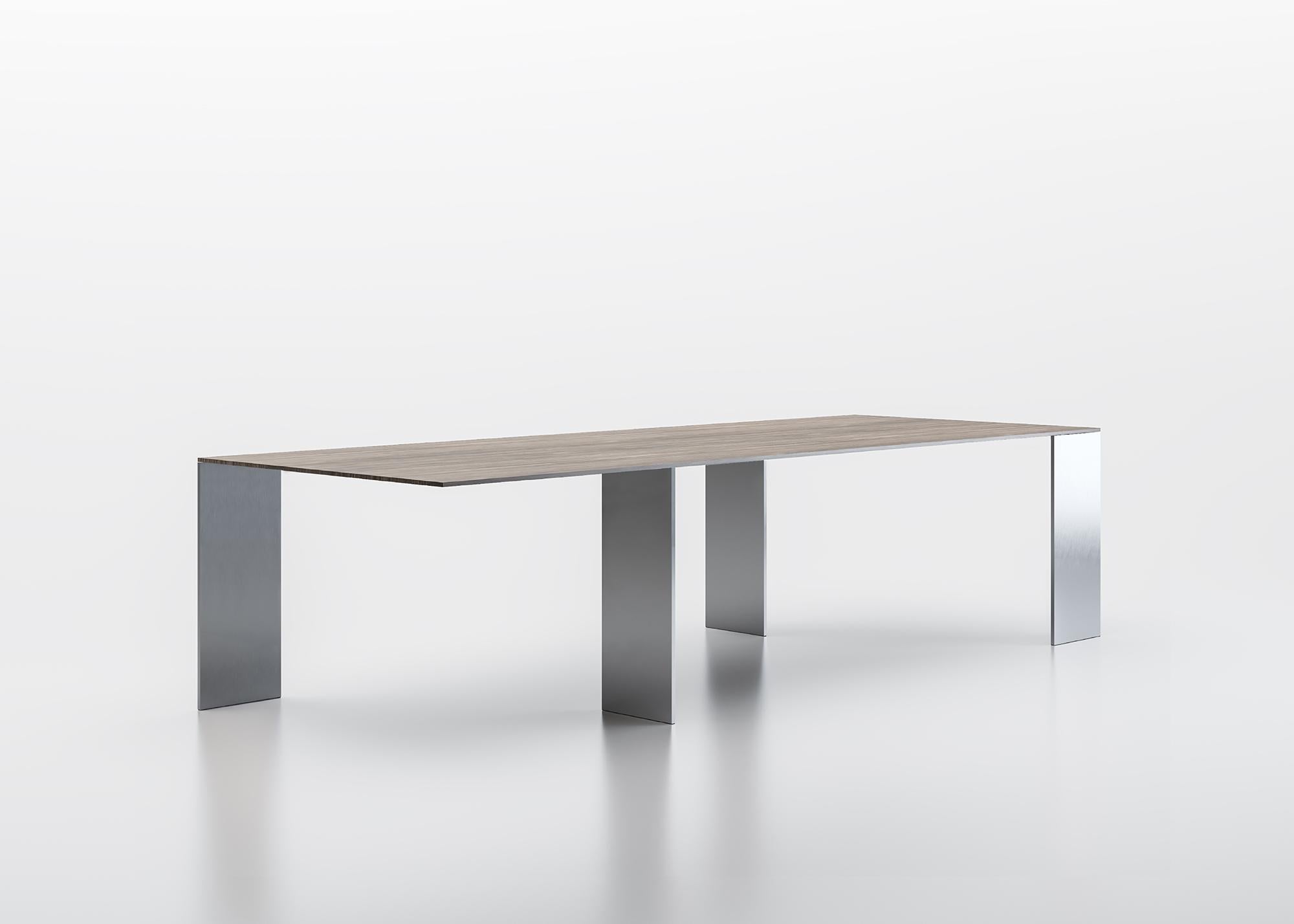 Table with extra-thin top, made of composite material veneered with precious woods, or in lacquered glass, supported by legs, placed onto opposite perpendicular axes. Wood top thickness mm 14, glass top in back-lacquered extraclear glass thickness