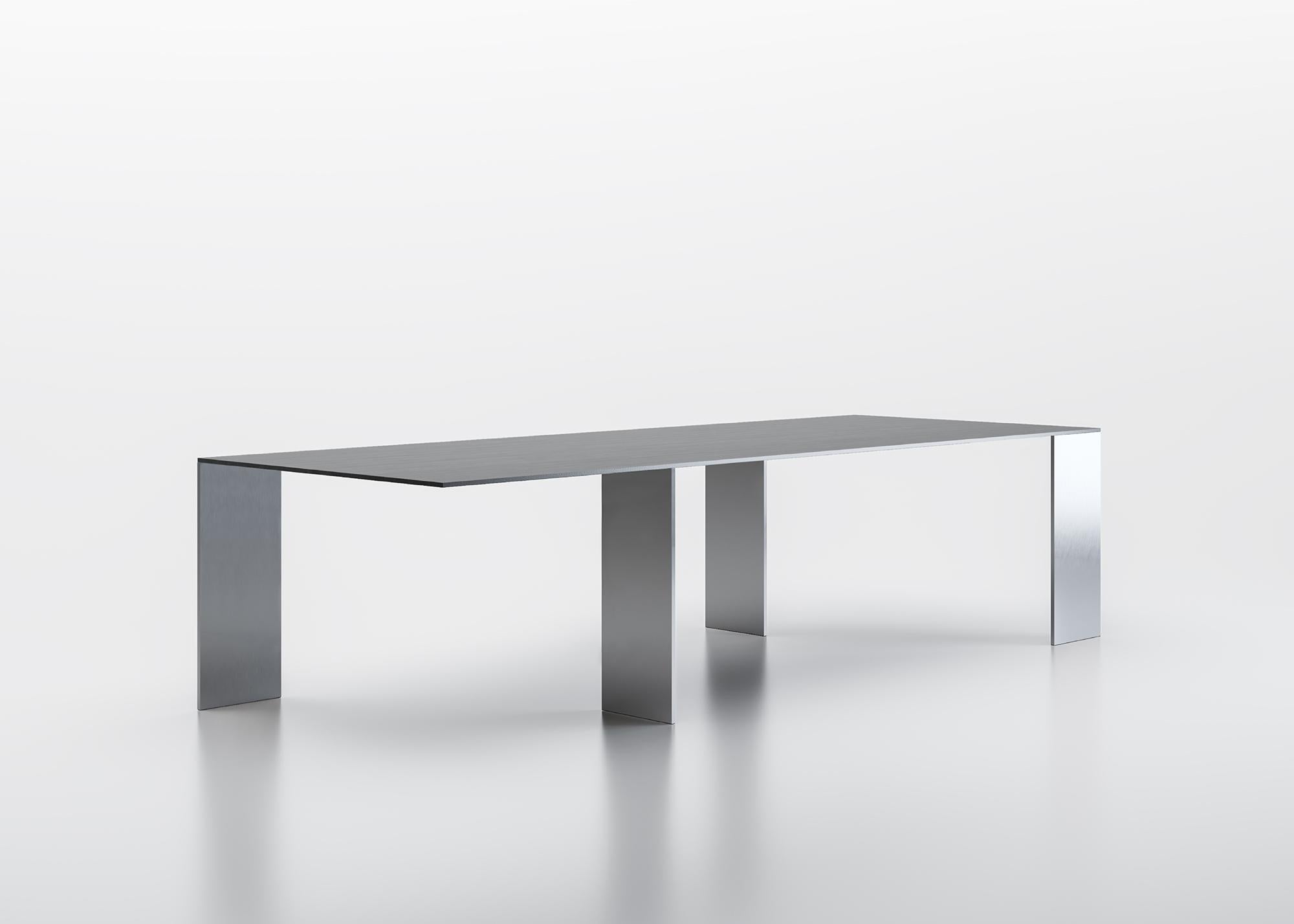 Table with extra-thin top, made of composite material veneered with precious woods, or in lacquered glass, supported by legs, placed onto opposite perpendicular axes. Wood top thickness mm 14, glass top in back-lacquered extraclear glass thickness