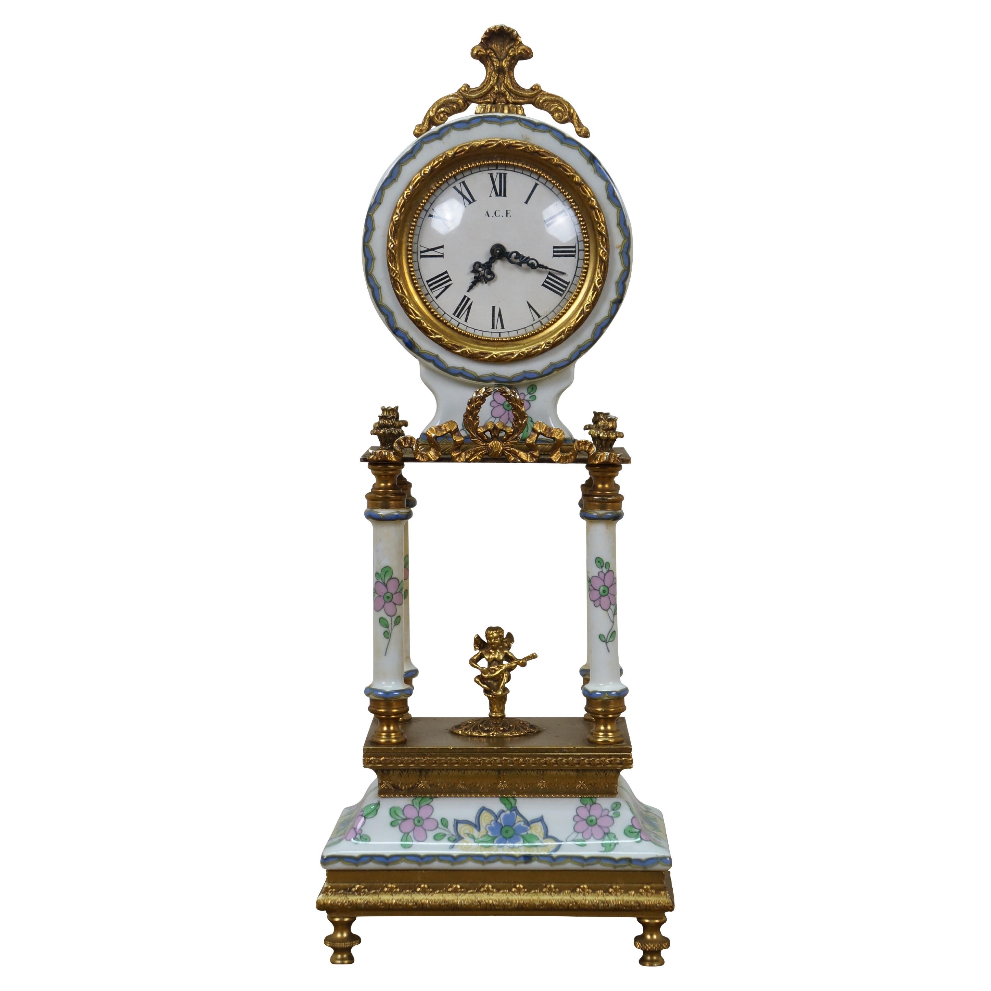 Vintage 20th century A.C.F. white porcelain and ornate gilt brass French limoge style mantel clock, hand painted with pink and blue florals. Rectangular base supporting four columns, flanking the figure of a small cherub or putti playing a stringed