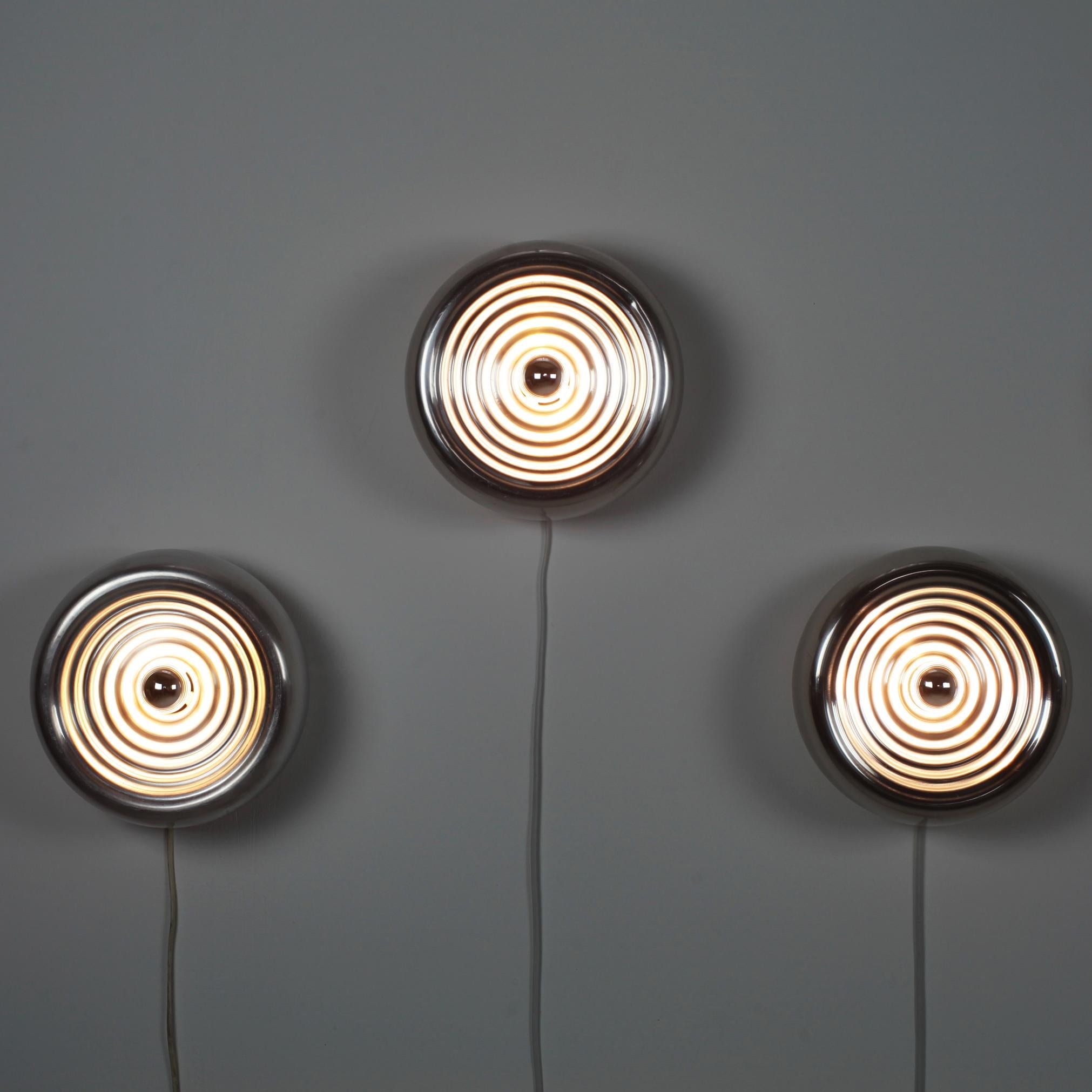 Beautiful set of 3 wall or ceiling lamps by Achille and Pier Giacomo Castiglioni manufactured by Flos in the late 1960s.
Polished corrugated spun aluminum.
No longer manufactured.
Iconic design.

Need E14 bulb.