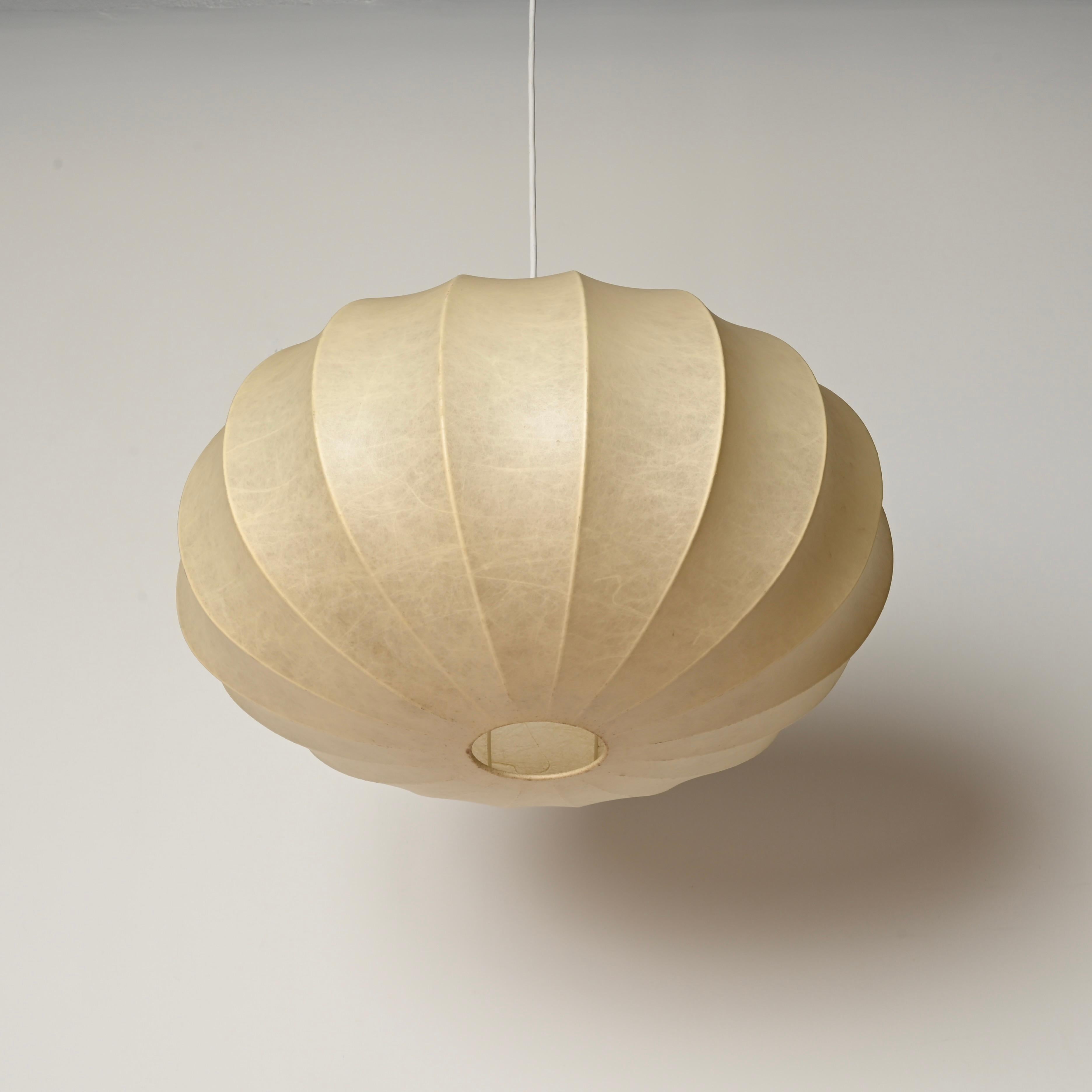 Marvelous mid-century beige cocoon pendant in resin and steel. This gorgeous ceiling lamp was designed by Achille Castiglioni in Italy during the 1960s.

In fabulous vintage condition, with a charming and evenly aged soft beige patina. This cocoon