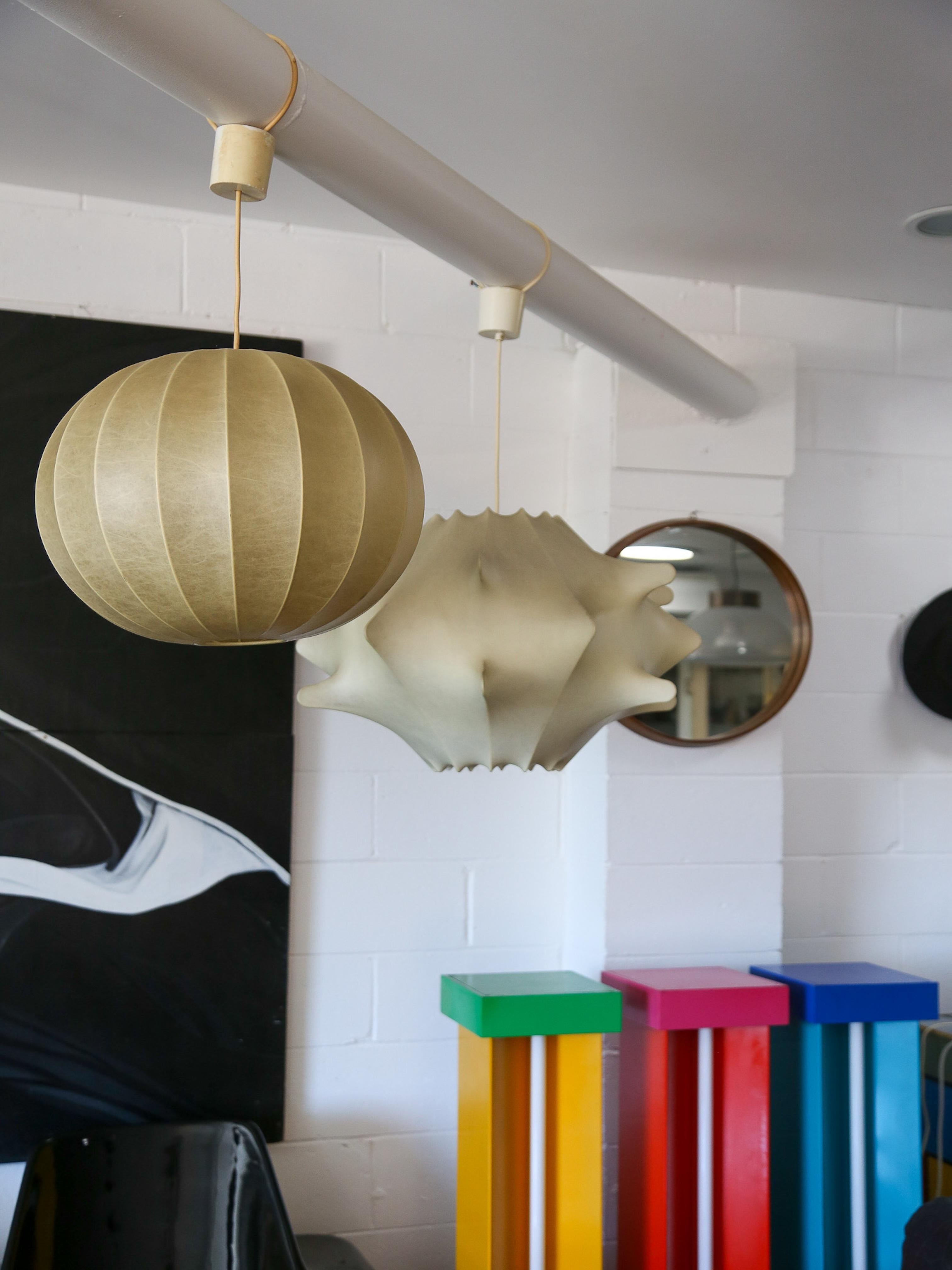 Achille e Pier Giacomo Castiglioni sono famosi designer italiani noti per i loro design innovativi e funzionali, in particolare nel campo dell'illuminazione. Una delle loro creazioni di spicco è la lampada a sospensione Cocoon, che esemplifica