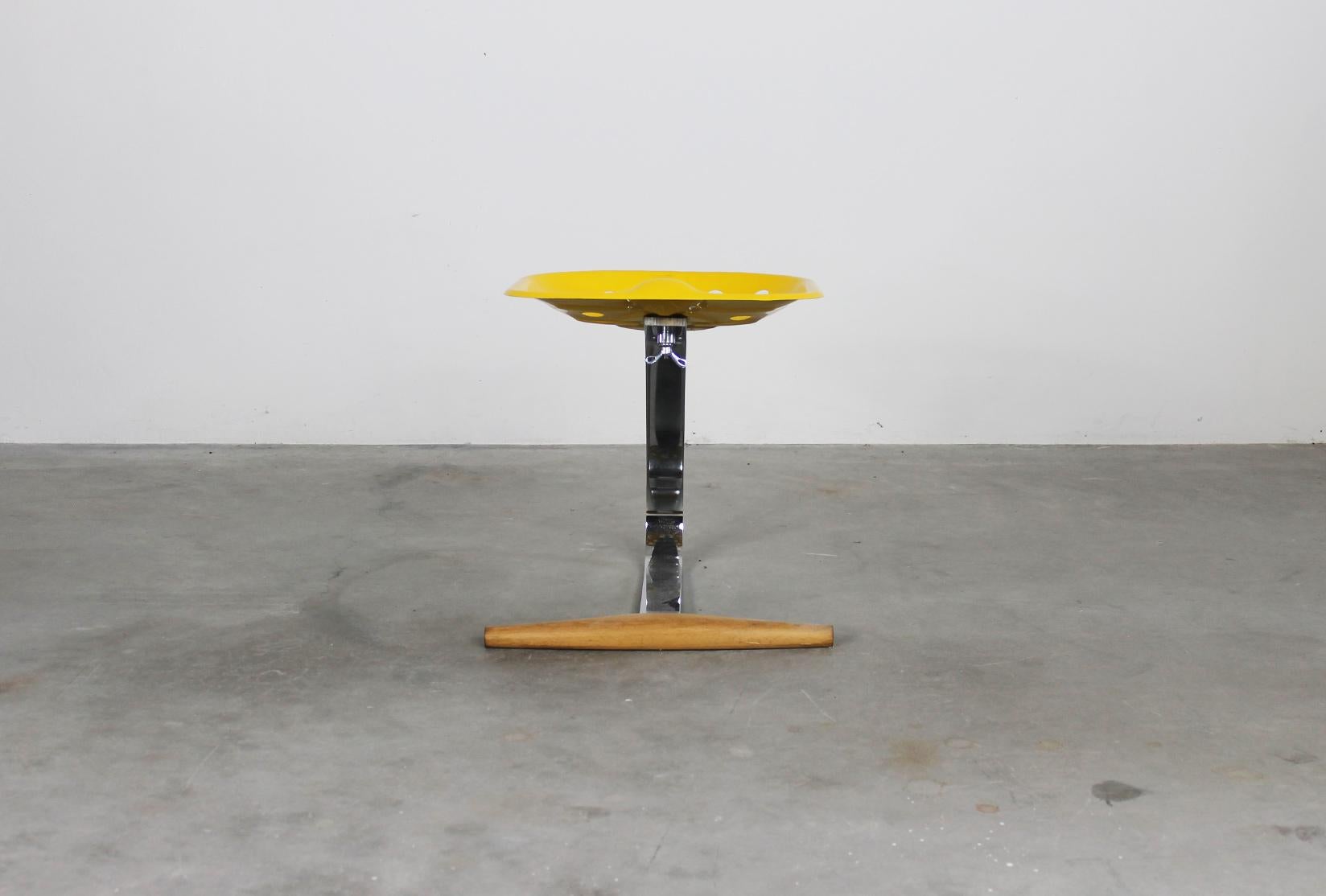 Mezzadro stool with chromium-plated steel stem, seat in yellow lacquered metal and footrest in beech wood. 
Designed by Achille and Piergiacomo Castiglioni in 1957 and produced by Zanotta in 1970s.

In 1970 Zanotta put the “springy metal seat”,