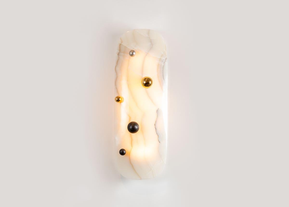 This wall mounted light fixture is crafted by designer Achille Salvagni out of a single piece of onyx. The piece is carved into a subtle convex curve, creating a perfect form, which, coupled with the soft, warm light given forth by onyx, suggests