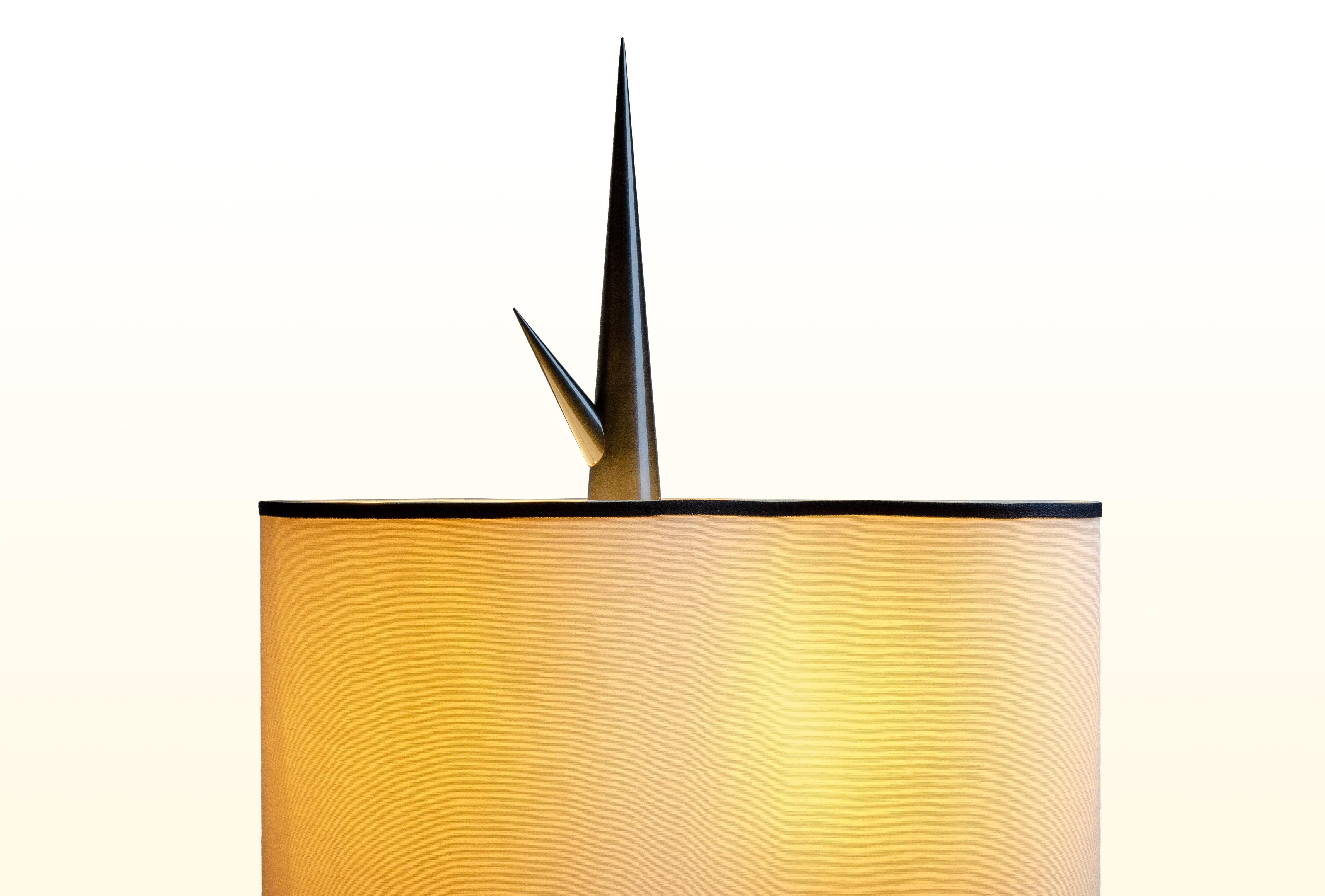 Achille Salvagni
Sting wood
2019

This table lamp has a nearly perfect conical shape for it's base and culminates at its top in a needle-sharp point. The lamp base is made of wood with a brass finial and an organic silk lampshade and feather