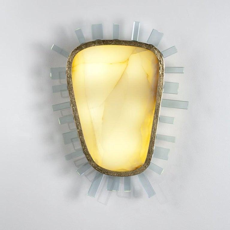 Valentine, a playfully dark sconce by Italian designer Achille Salvagni, is made up of a beautifully translucent, heart shaped stone, a hand hammered, patinated bronze frame, and a ring of shard-like glass pieces which jut from its sides in regular
