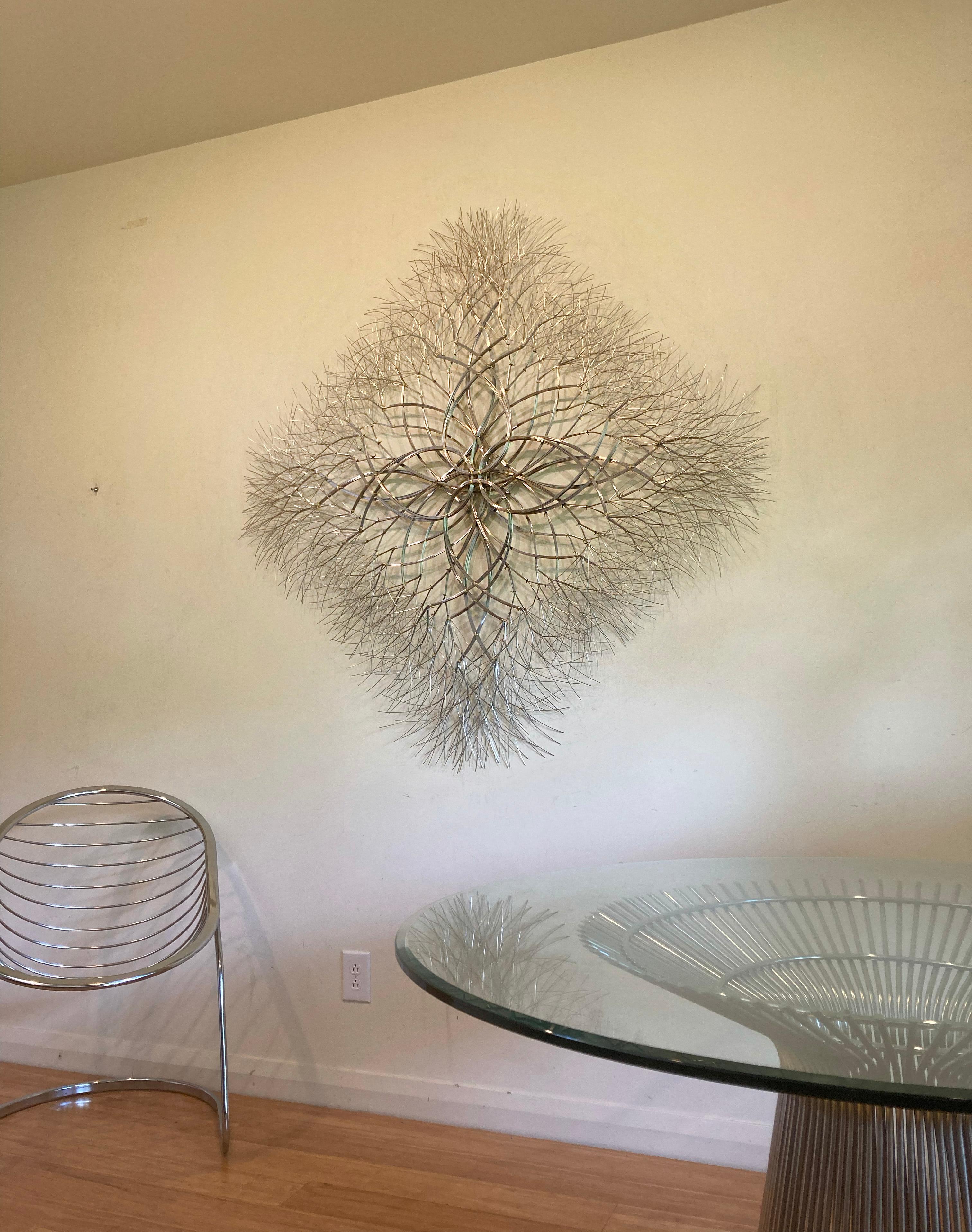 This abstract geometric sculpture by Kue King is created using stainless steel wire. Kue uses an aesthetic reminiscent of trees, electricity, and light to create sculptures of peace and beauty. Adults and children alike see snowflakes, stars,