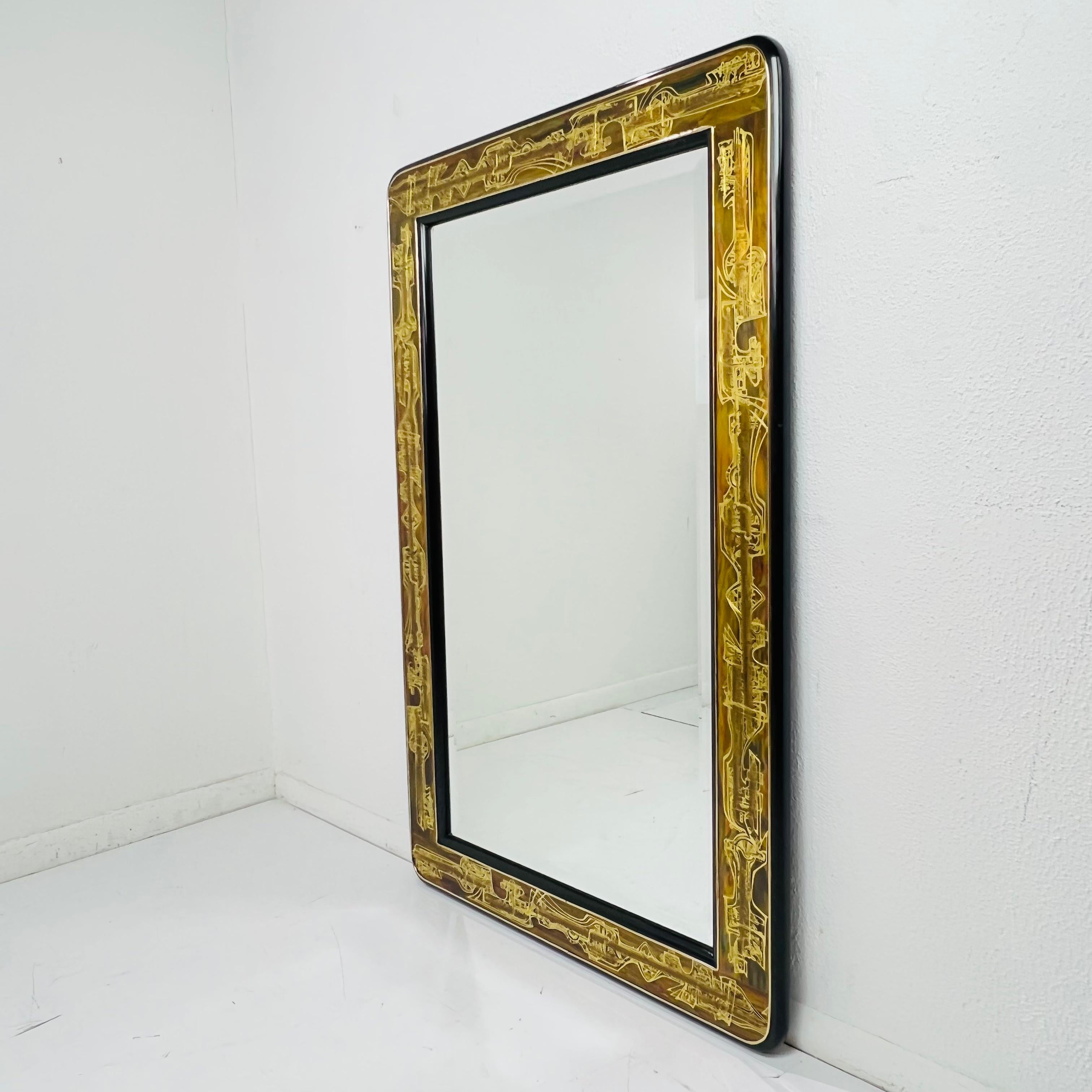 This sophisticated wall mirror was designed by Bernard Rohne and realized for the esteemed American maker, Mastercraft, circa 1970. The brass interior of the frame features organic and futuristic acid etched detailing and is framed on either side by