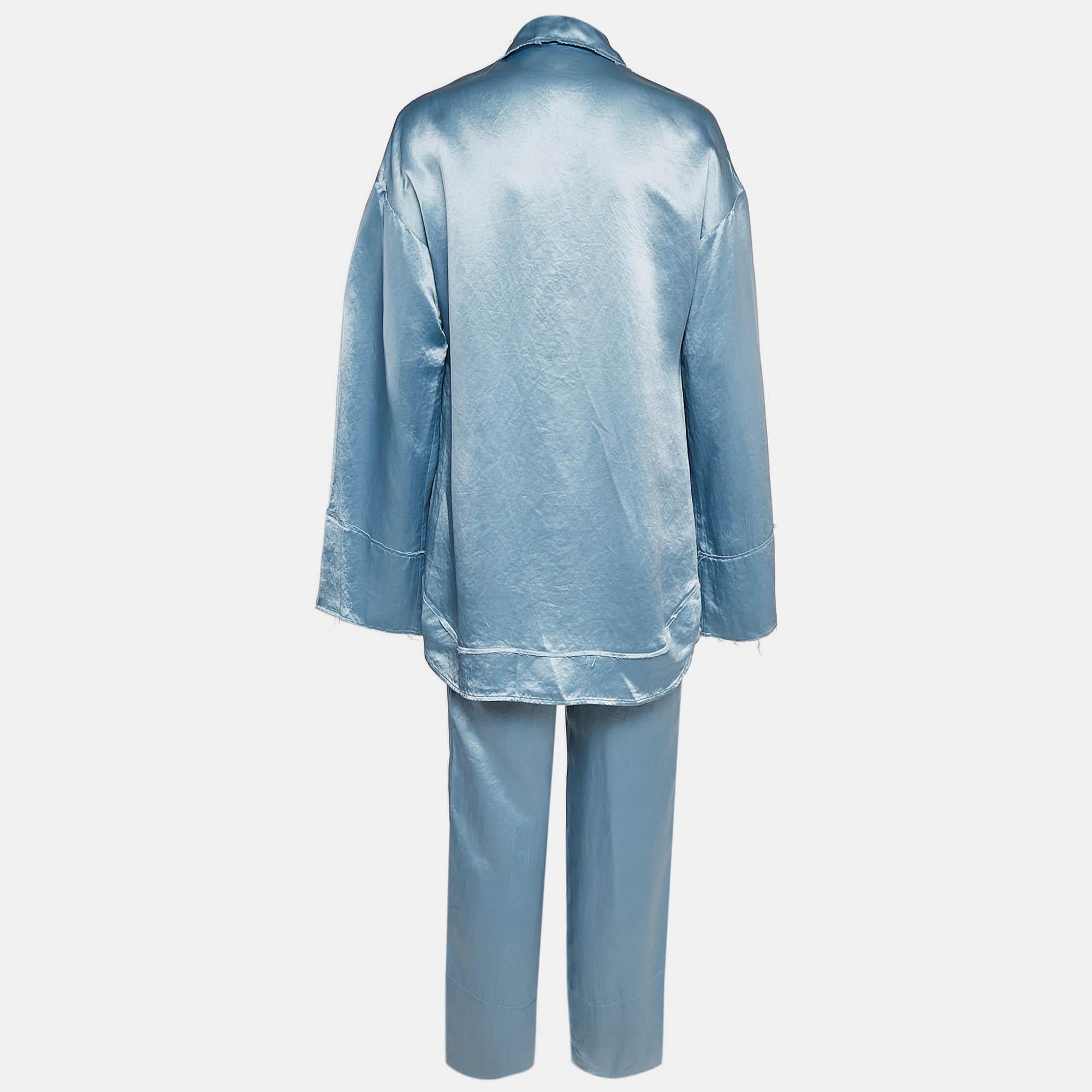 The Acne Studios shirt and trousers set in satin features a fluid  relaxed fit shirt paired with matching trousers  creating a seamless  sophisticated silhouette. The soft blue hue enhances the elegance of the design  while the lightweight fabric