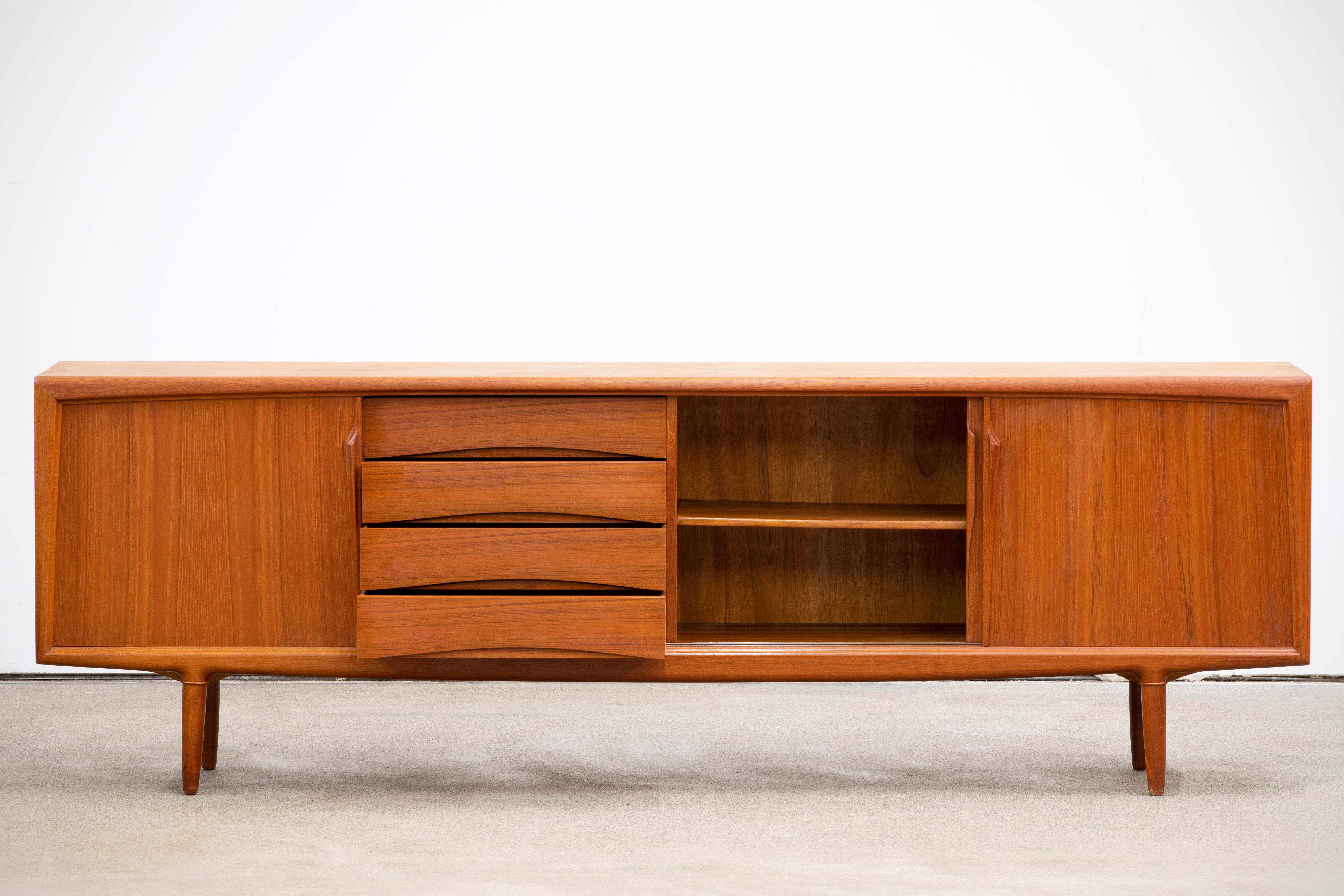 Ce buffet de Gunni/One est un véritable classique du mobilier danois. Le modèle représentatif numéro 13 est fabriqué en teck de très haute qualité et est dans un état exceptionnellement bon. Le point fort du meuble est le design de la partie avant :