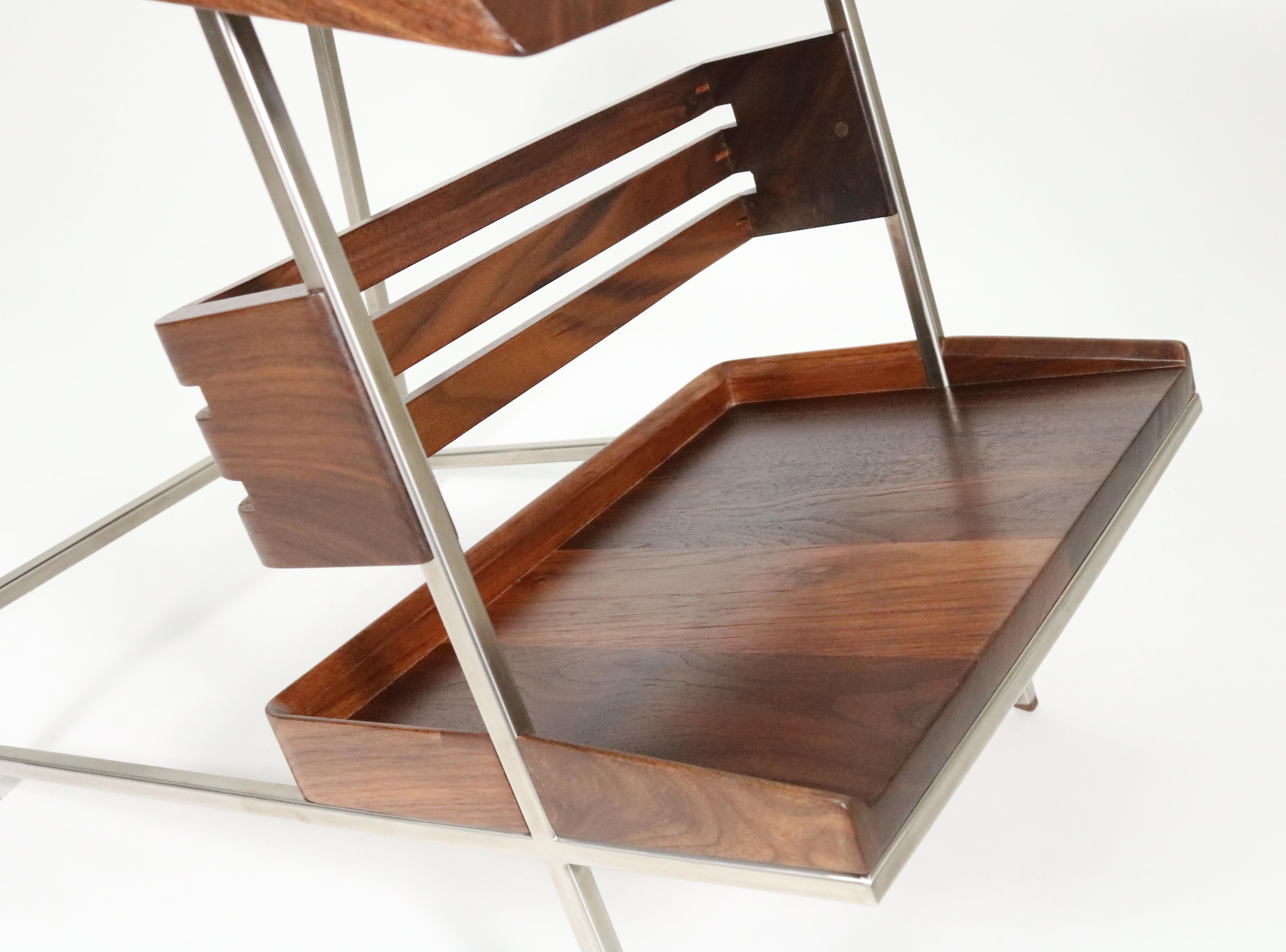 Form married to function in walnut and padauk in this handsomely modern side table by Boulder, Colorado designer Alexander Giray. 

The floating shelf provides display of your favorite books, while drawing your eye to the table's unique design and