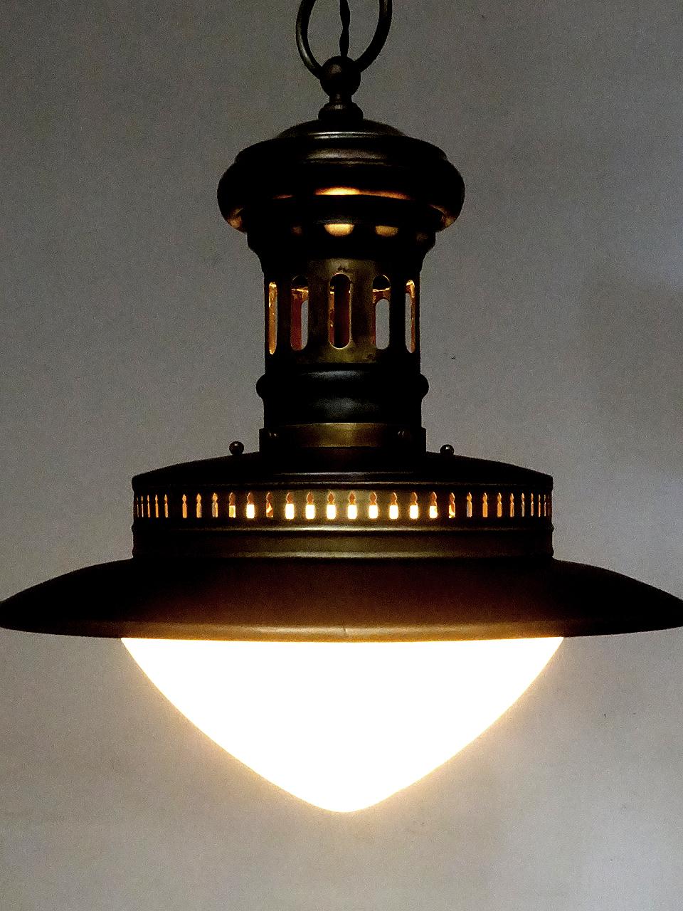 This is an interesting gas lamp with a unique wide shape. Its constructed with a combination of galvanized steel and brass showing nice subtle color changes. The large acorn shade is white milk glass and gives a nice even glow. There are decorative