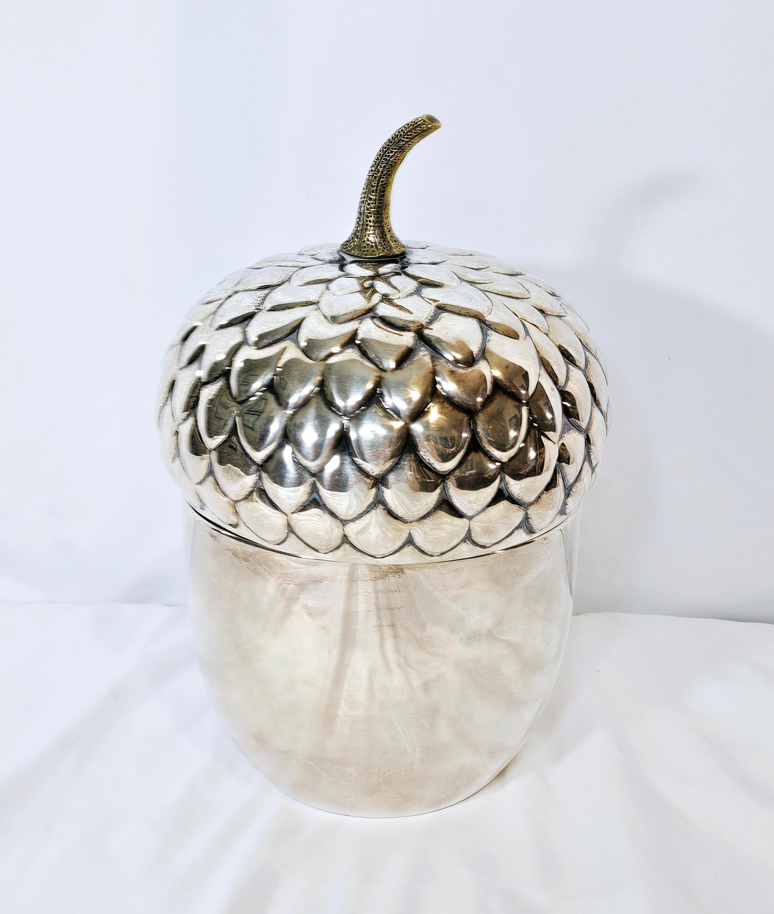 Bold.
Figurative. 
Sleek.
Teghini Firenze designed this lovely modernist silver plated ice bucket in the 1960s. 
The piece features a rounded shape with an oversized stylized acorn design with a lid and a white plastic insert. 
There is a visible