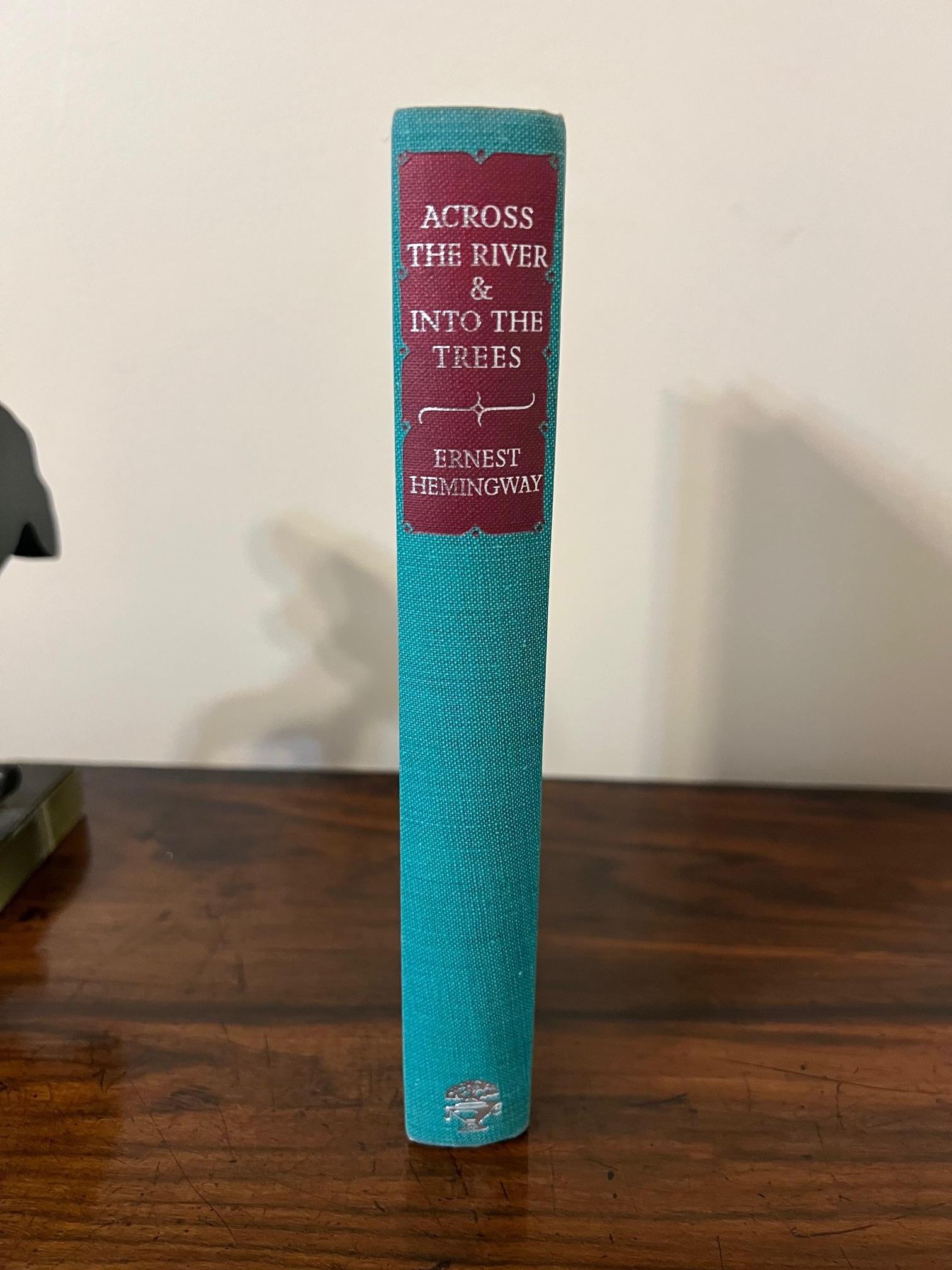 Al otro lado del río y entre los árboles
por Ernest Hemingway
Publicado Jonathan Cape, Thirty Bedford Square, Londres, 1950
Verdadera primera edición inglesa que precede en 4 días a la primera edición americana. 
Con sobrecubierta en excelente