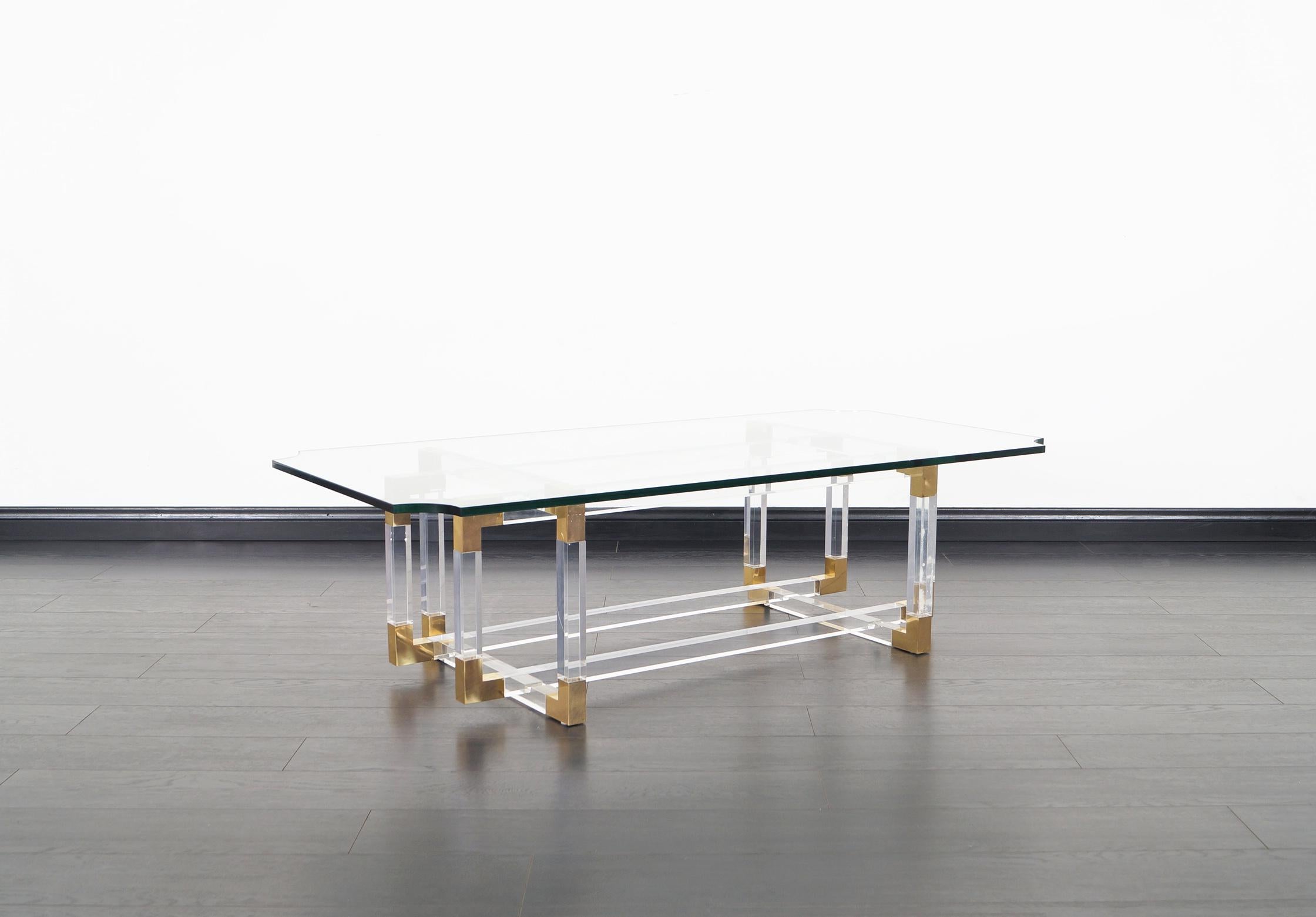This stunning vintage Lucite and brass coffee table designed by Charles Hollis Jones, part of his 
