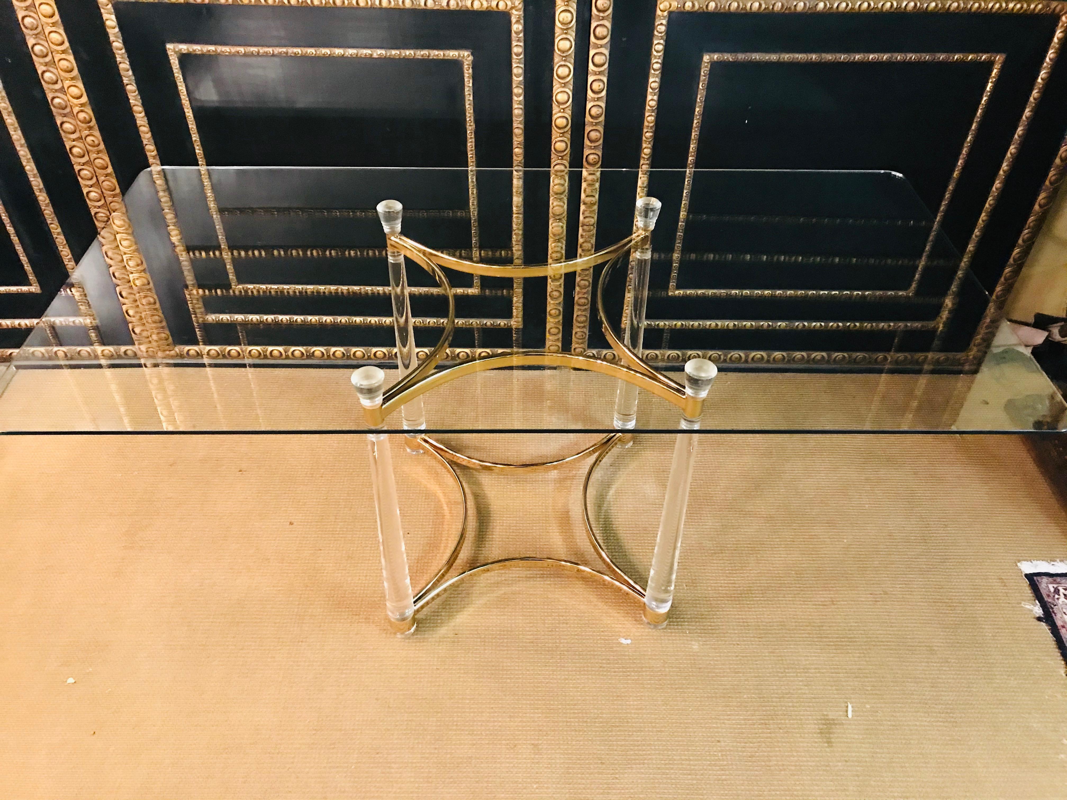 High quality acrylic dining table with acrylic columns legs, the legs are connected at the bottom with a brass frame. 
Rectangular glass plate.

 