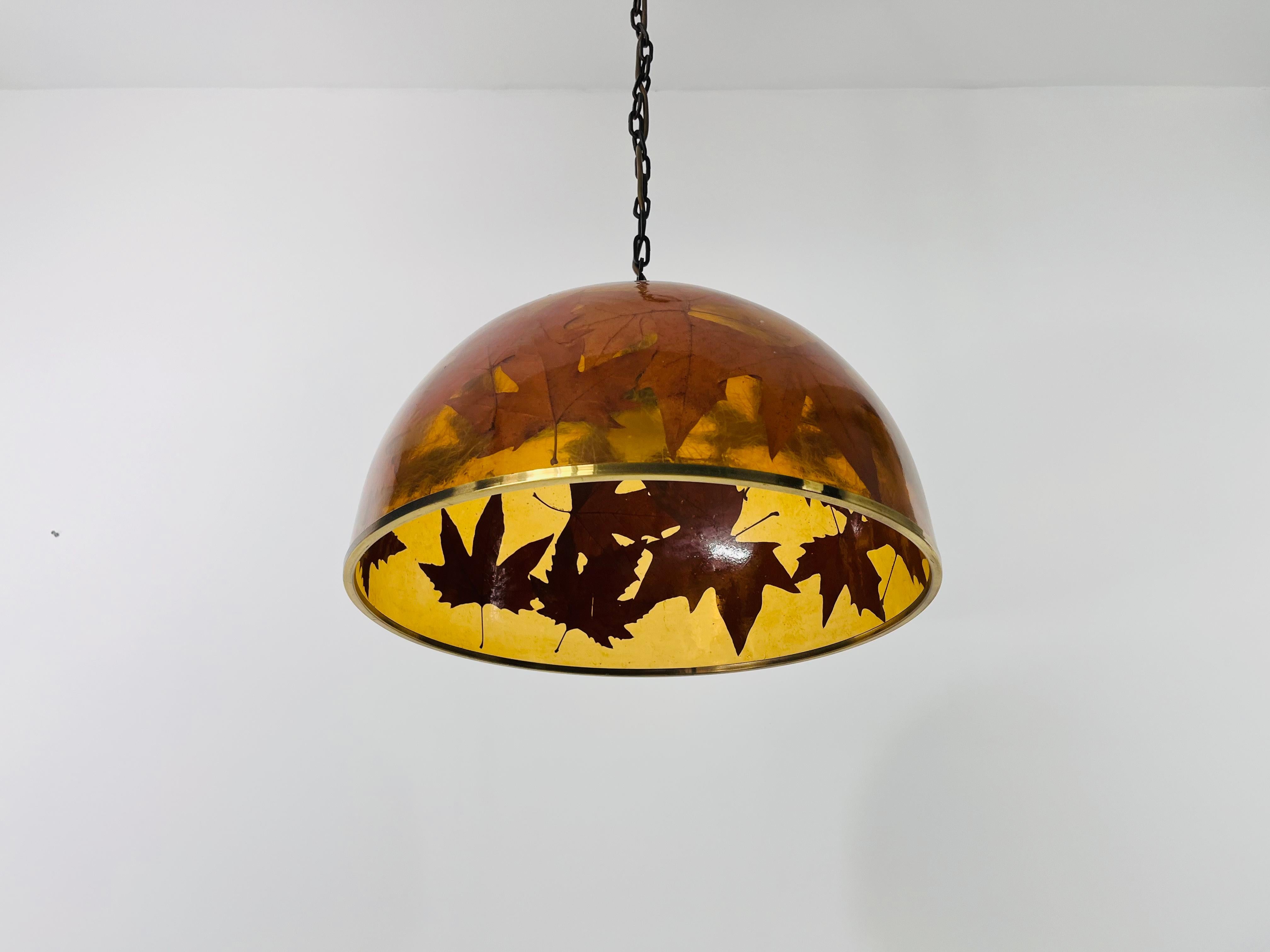 Una straordinaria lampada a sospensione in vetro acrilico con foglie vere nel vetro. È stato realizzato nel periodo di Hollywood Regency. L'anello della base è in ottone.

Misure:

Altezza: 28-210 cm
Diametro: 45 cm

La lampada richiede una