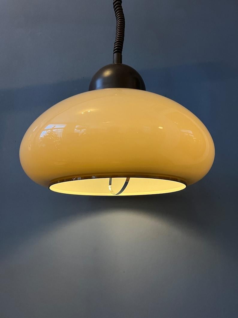 Suspension space age du milieu du siècle par Dijkstra avec abat-jour en verre acrylique beige. La hauteur de la lampe peut être facilement réglée grâce au mécanisme de montée et de descente. La lampe nécessite une ampoule E26/27.

Informations