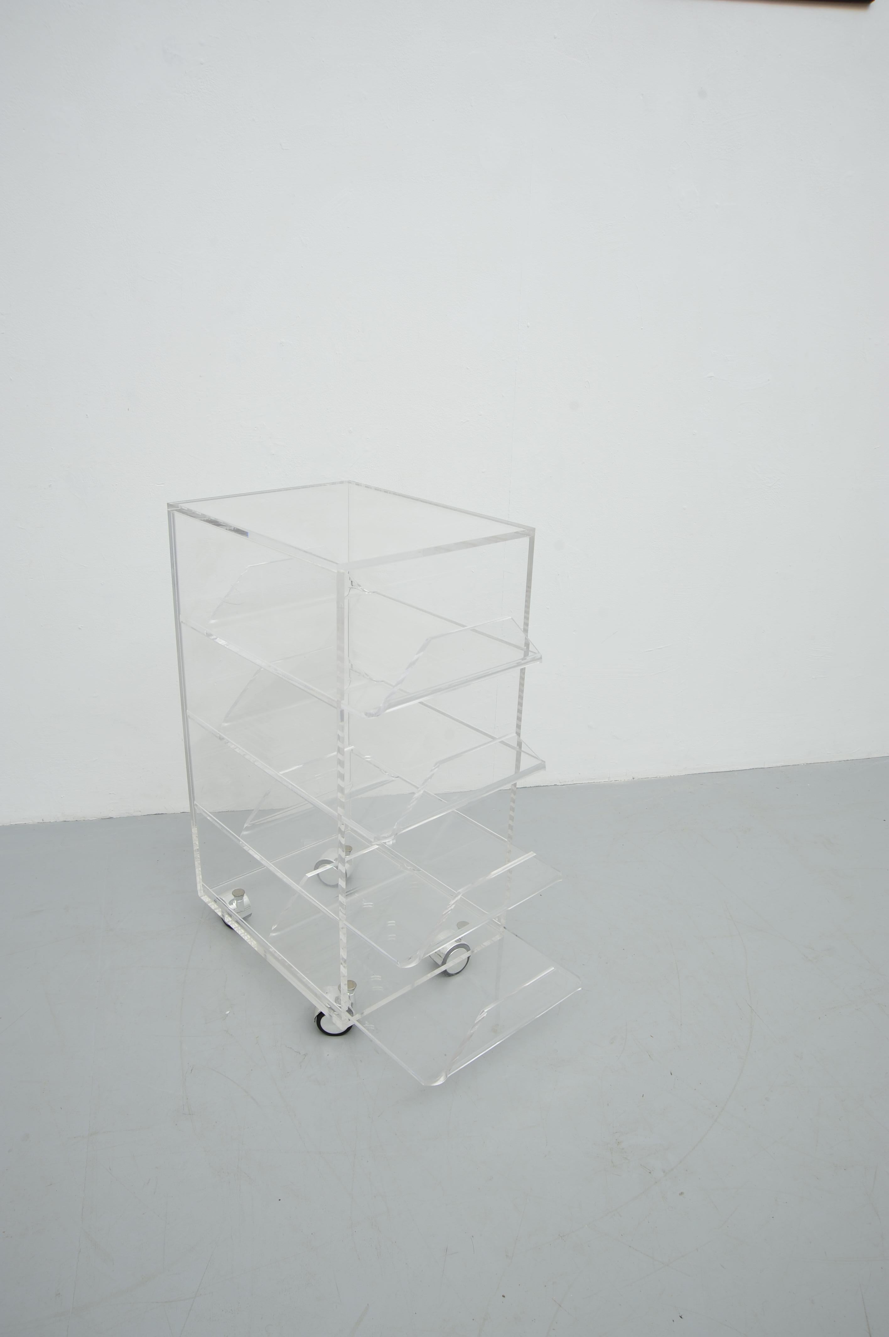 This sleek and modern acrylic rolling table features four spacious drawers, combining functionality with minimalist aesthetics. Its transparent design offers a clean, contemporary look, making it a versatile piece suitable for a variety of spaces,