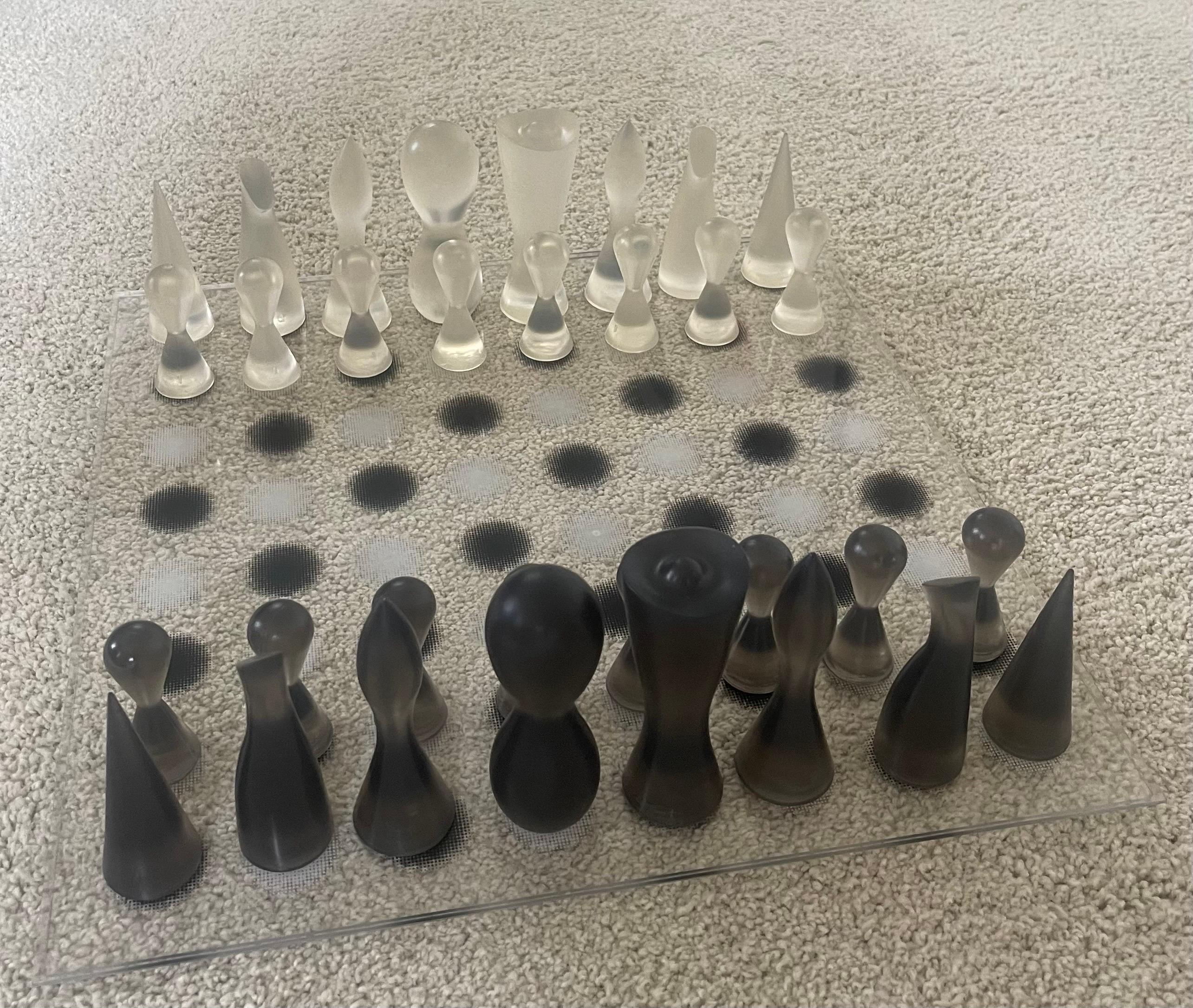 Beautiful and rare acrylic and rubber modern chess set by Karim Rashid, circa 2002. The set is in brand new condition and comes in original box with brochure. The sculptural and artistic black and clear chess set is hard to find and out of