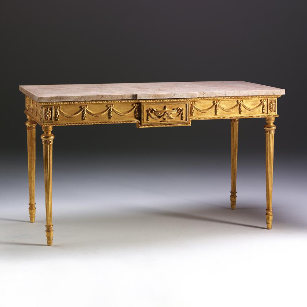 In the manner of Robert Adam (1728-1792), this elegant side table has a breakfront marble top which sits above a moulded frieze decorated with ribbon tied swags, centred by a rectangular tablet carved with a classical urn. The turned and tapered,