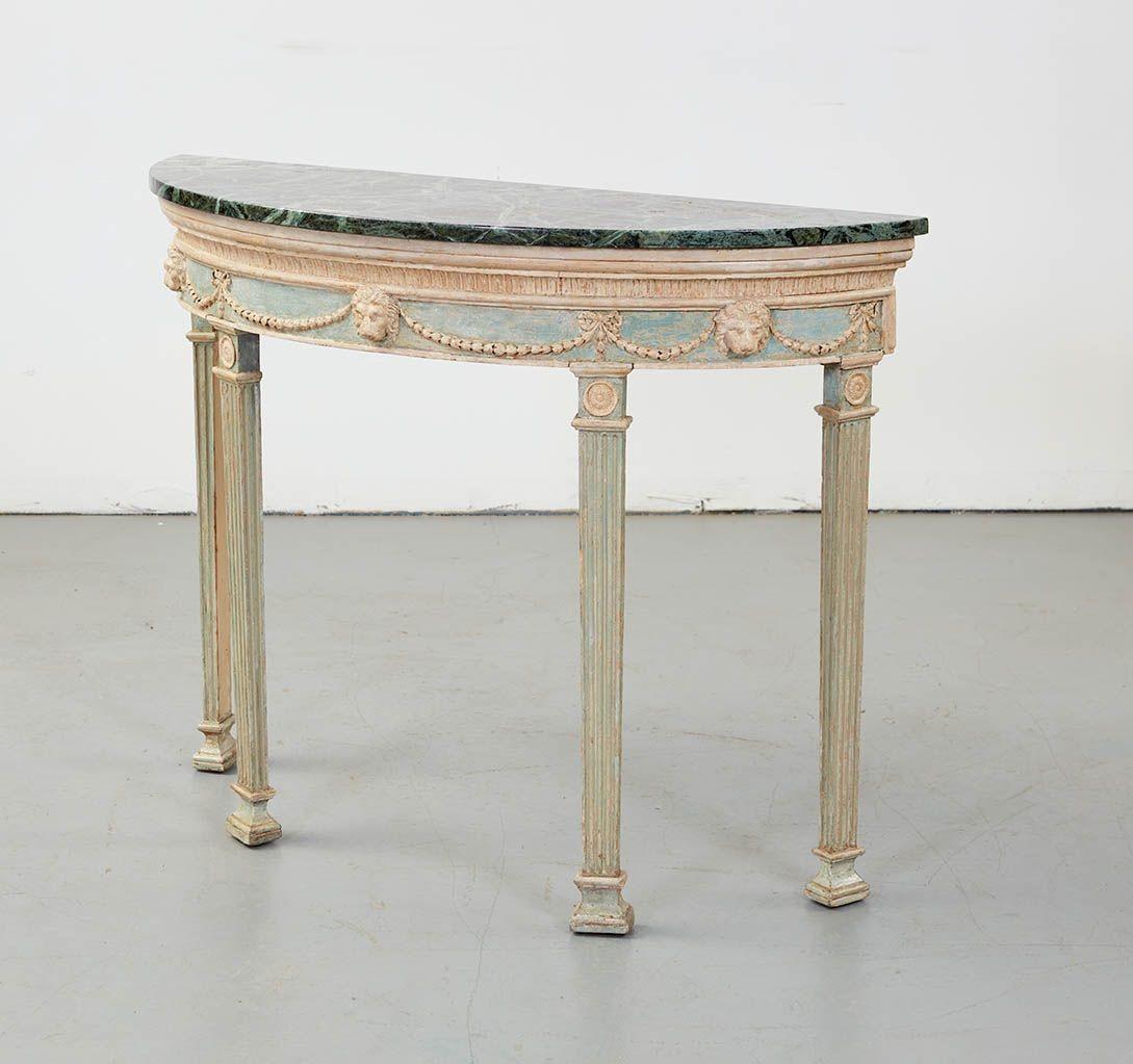 Very fine George III demilune console table, in the manner of Robert Adam, the later marble top over lamb's tongue carved molding over frieze decorated with lion masks and bell flowers, standing on pilaster legs with turned roundels and fluted