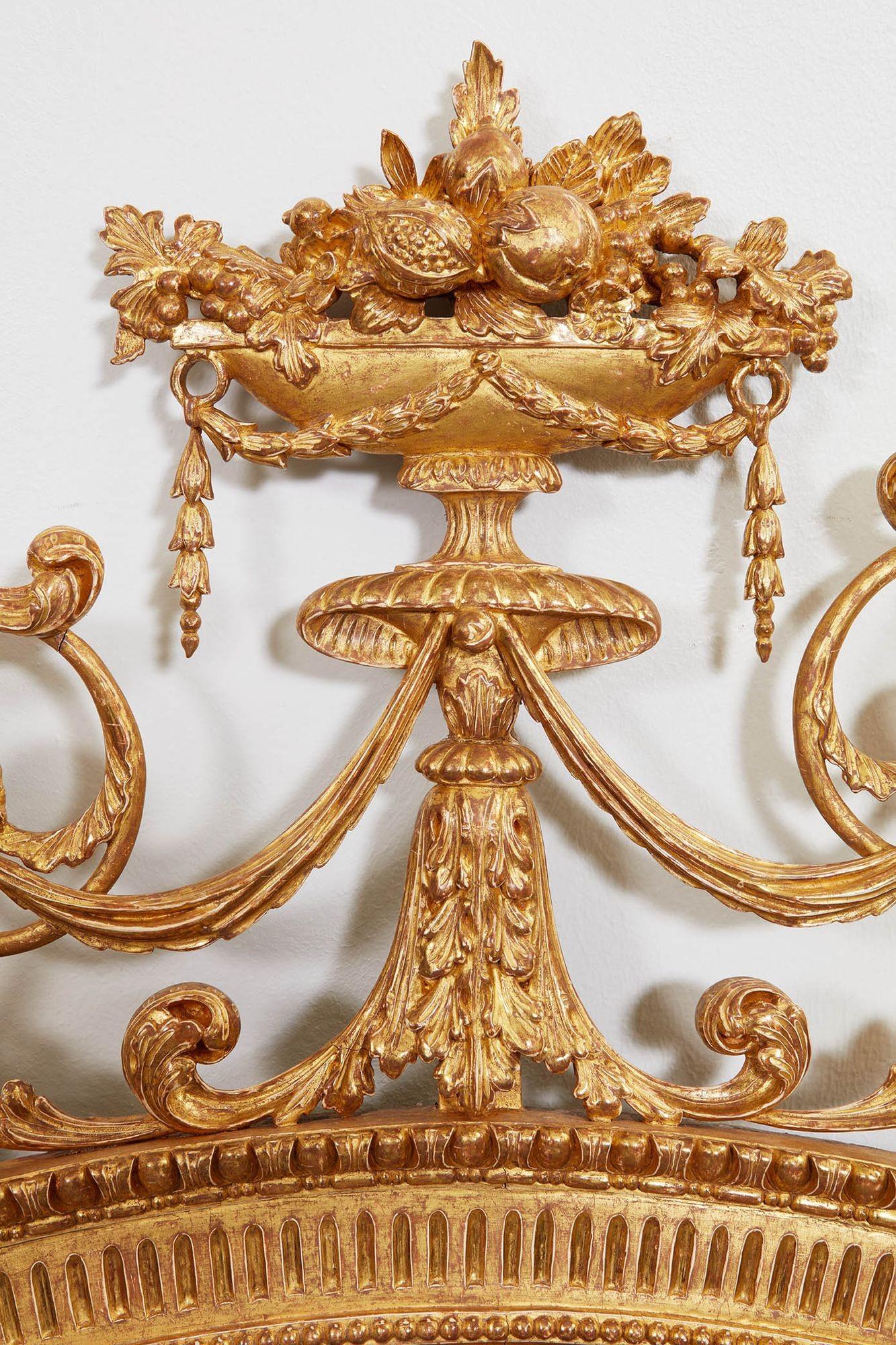 Very fine George III oval neoclassical mirror with flowering urn finial draped with bellflower garlands, over acanthus leaf carved base, having festoons and scrolls, over fluted oval frame with egg and dart and beaded carving, standing on lion paw
