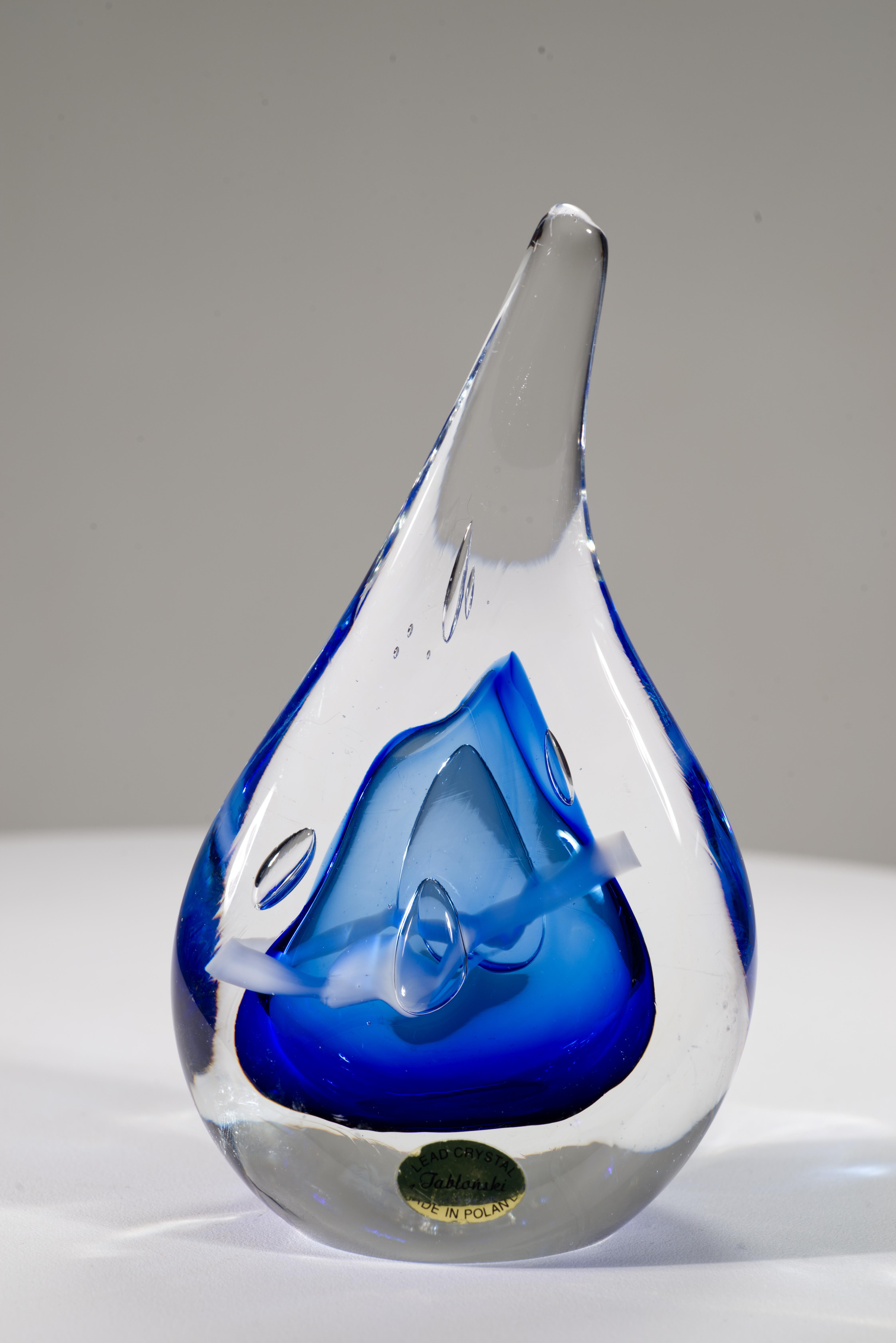  Colorful abstract art glass sculpture or paperweight features flattened teardrop shape with central core of cobalt blue and white colored glass with controlled bubbles, enclosed in a layer of clear glass in sommerso technique.

The piece is signed