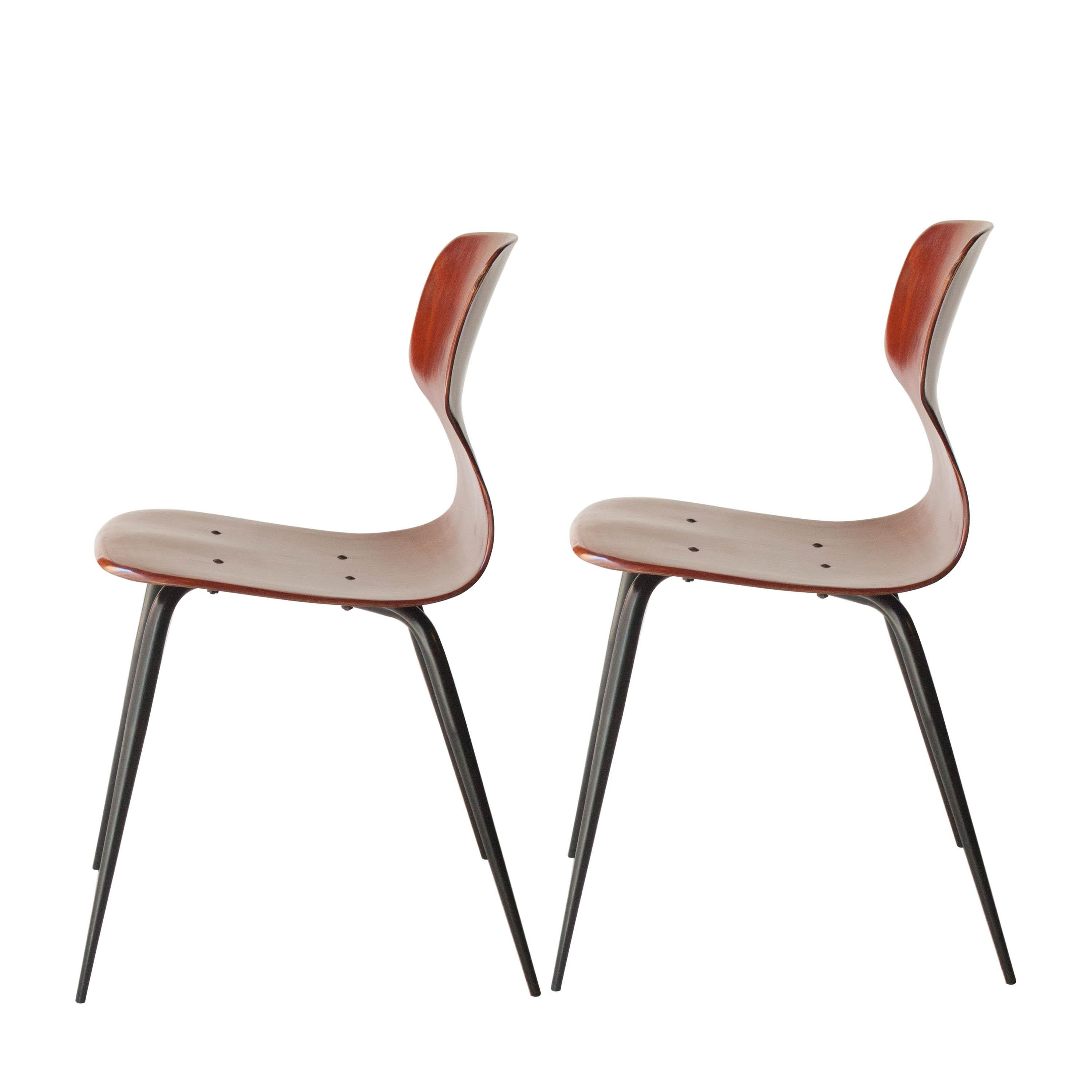 Two chairs designed by Adam Stegner for Pagholz Flo¨totto. Made in high density laminated compressed wood and lacquered iron tapered legs. Artful formed seat with ornamental cutout.