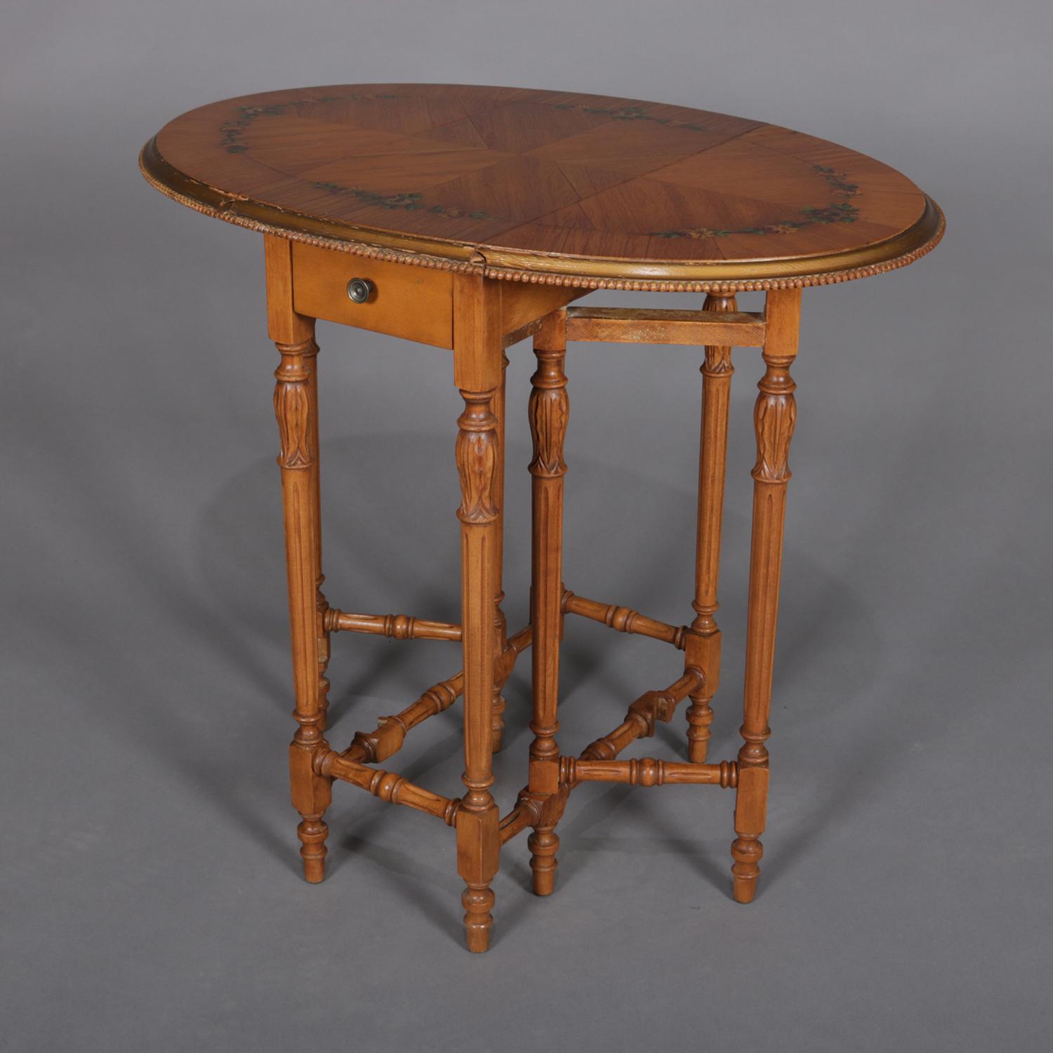 An Adam style Pembroke end stand features satinwood construction with bookmatched drop leaf top with hand painted foliate decoration and having carved beaded bordering and surmounting single drawer case raised on turned gate leg base, 20th