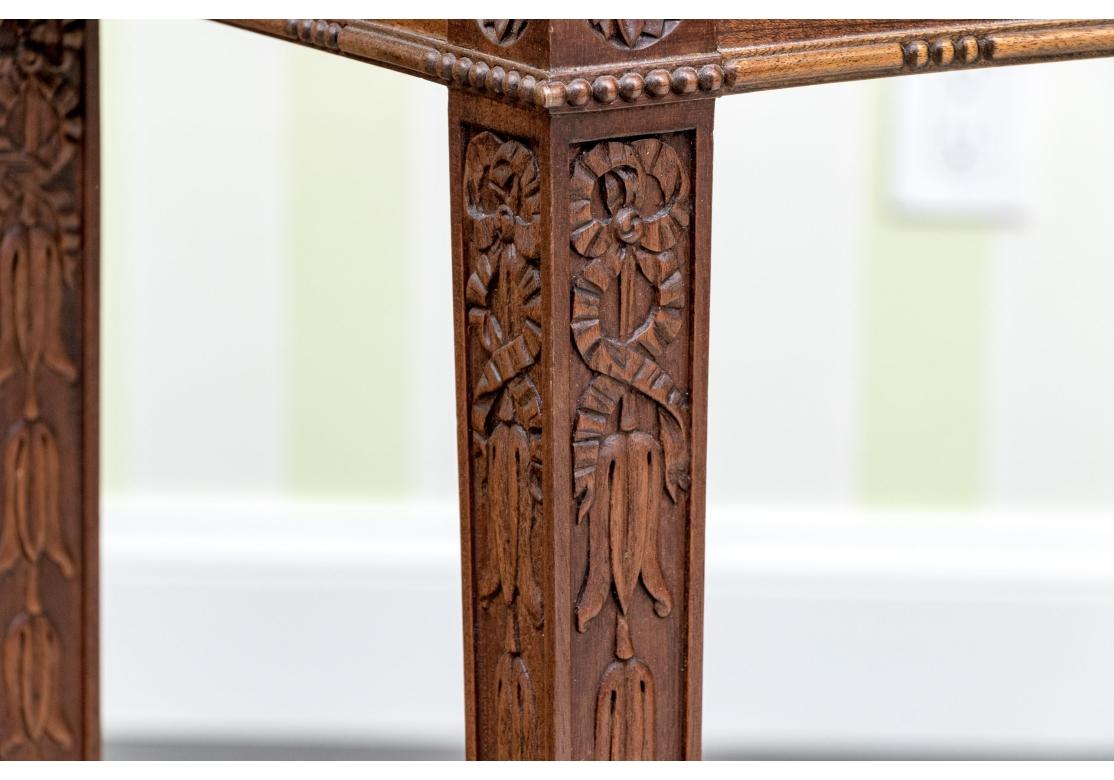 Elaboradamente decorado  Mesa consola  de tamaño diminuto que conserva una forma elegante. Consola tallada de estilo Adam neoclásico con tablero en forma de toro que descansa sobre un delantal conformado con un friso muy tallado que presenta