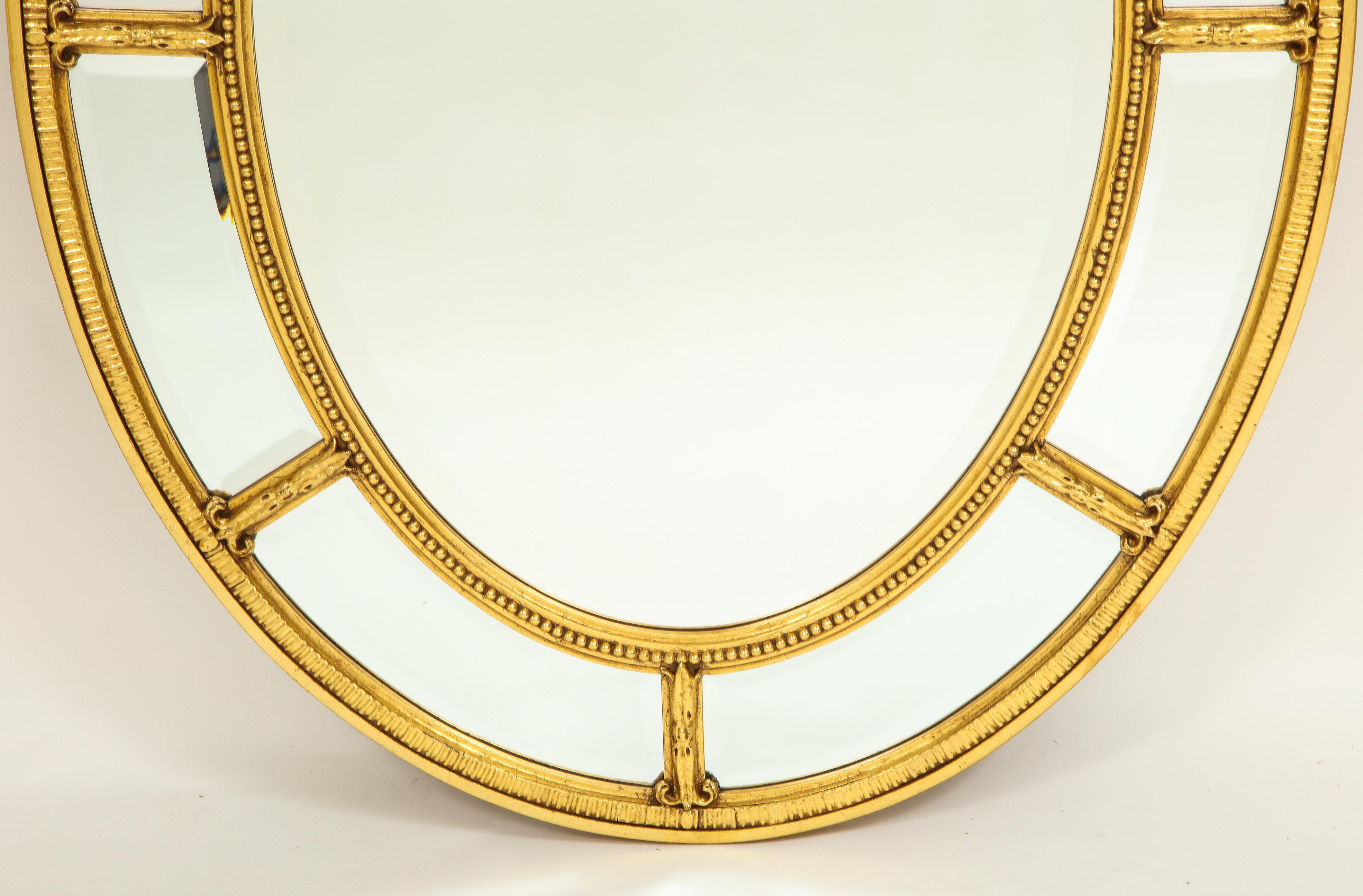 The oval mirror plate surrounded by border plats within a beaded frame.